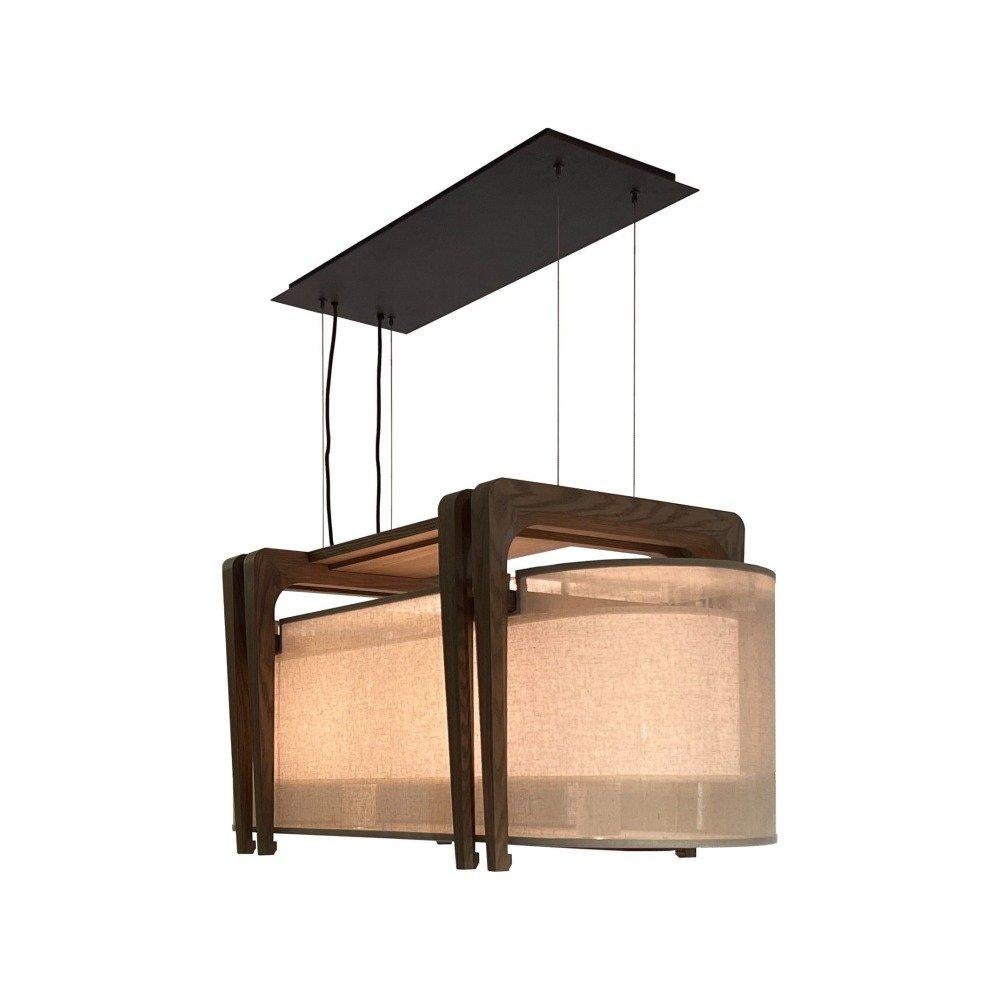 une suspension ovale conçue pour évoquer un fort sentiment de luxe discret. fabriquée avec la lanterne signature de fu, composée de deux couches d'abat-jour en tissu, chaque lampe évoque une lueur sensuelle pour rehausser tous les intérieurs.