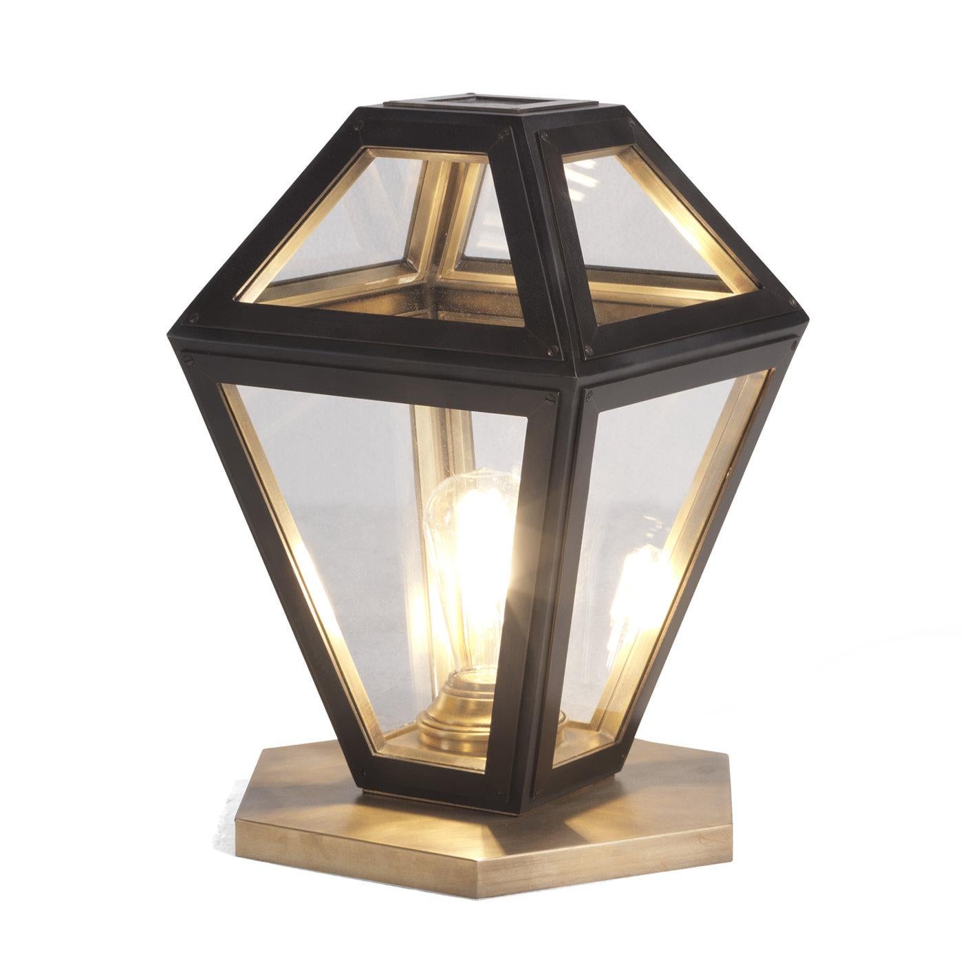 A unique piece of classic sophistication, this table lamp is part of a collection that reproduces the traditional shape of lanterns. Fashioned of brass frame encasing clear glass panels, this piece rests on a hexagonal base that recalls the lantern