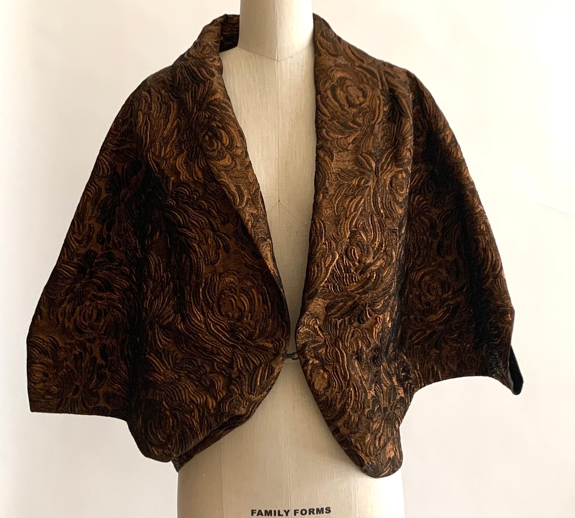 Lanvin 2009 by Alber Elbaz copper floral brocade cape-like jacket. Armholes at side. Single hook and eye closure at front.

46% wool, 35% acetate, 10% polyamide, 9% polyester.
Fully lined in 100% silk.

Made in France.

Labelled size FR 42,