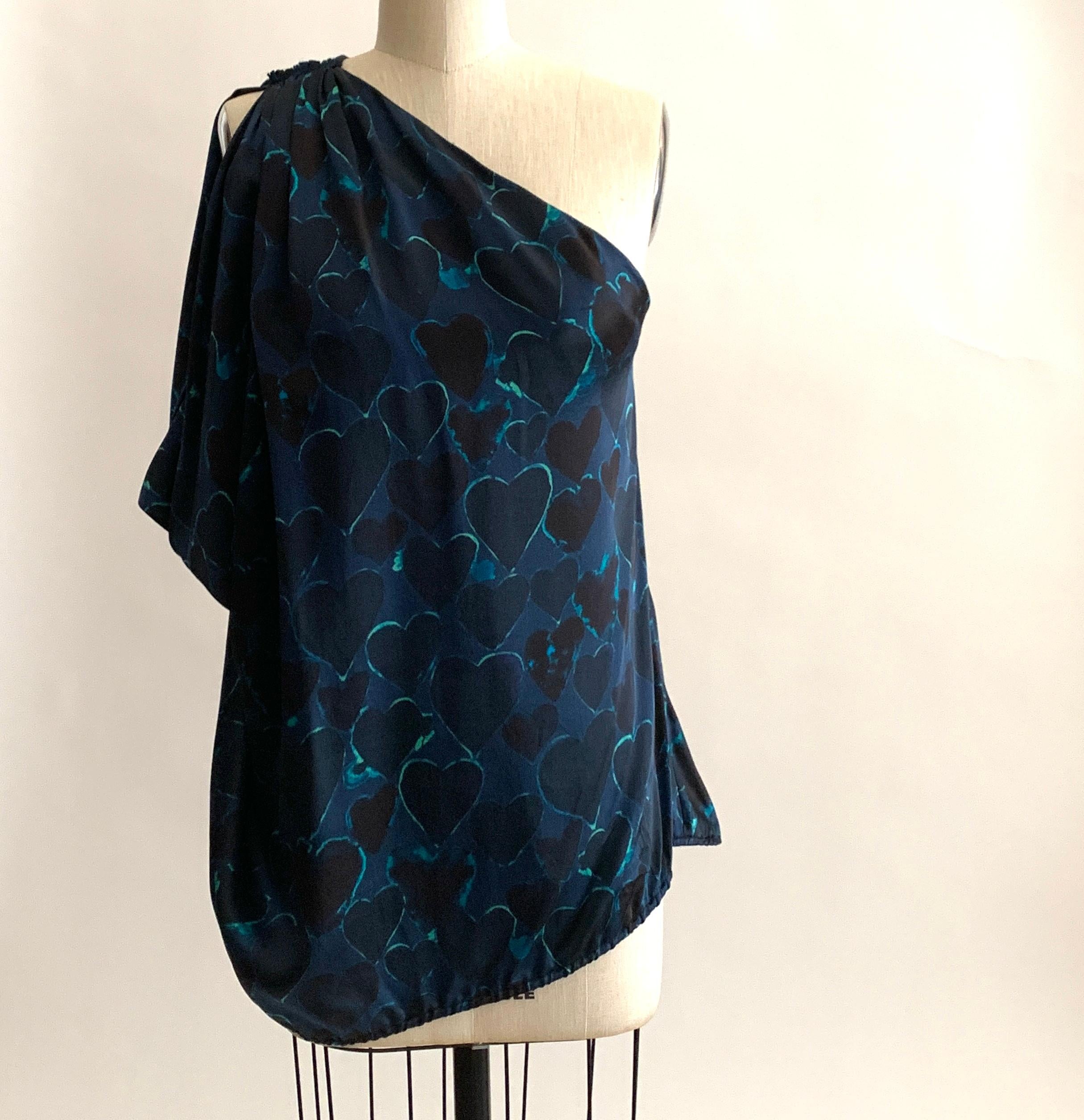 Lanvin heart print top in blue featuring black hearts outlined in a bold green hue. One shoulder with pleat detail at seam, loosely gathered elastic at hem creates a blousy fit.

100% silk.

Made in France.

Size FR 38, approximate US 6, but size is