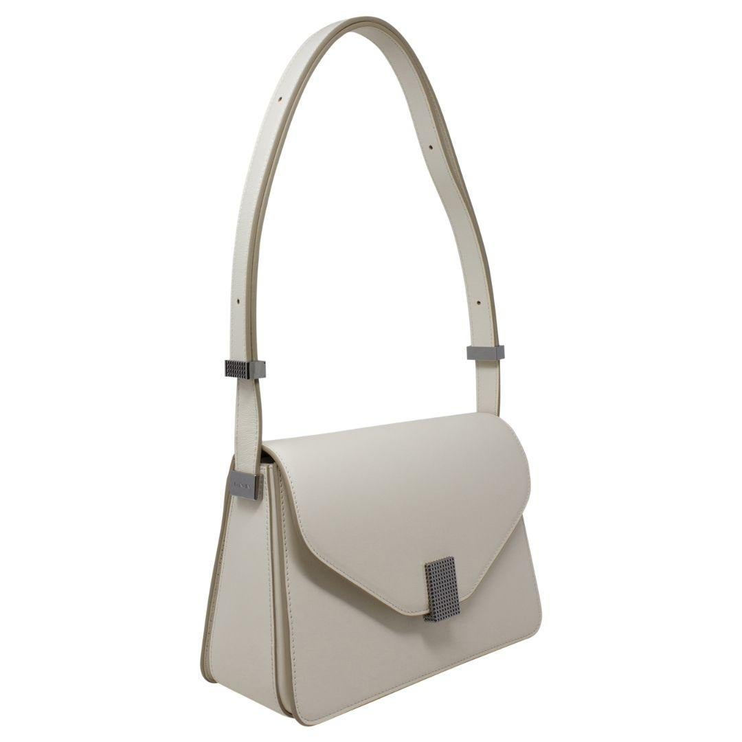 This ivory calfskin leather bag, accented with silver hardware, is both elegant and practical. The snap closure ensures security, and the two interior slip pockets offer ample space to organize your essentials efficiently.

SPECIFICS
• Length: 9.2
•
