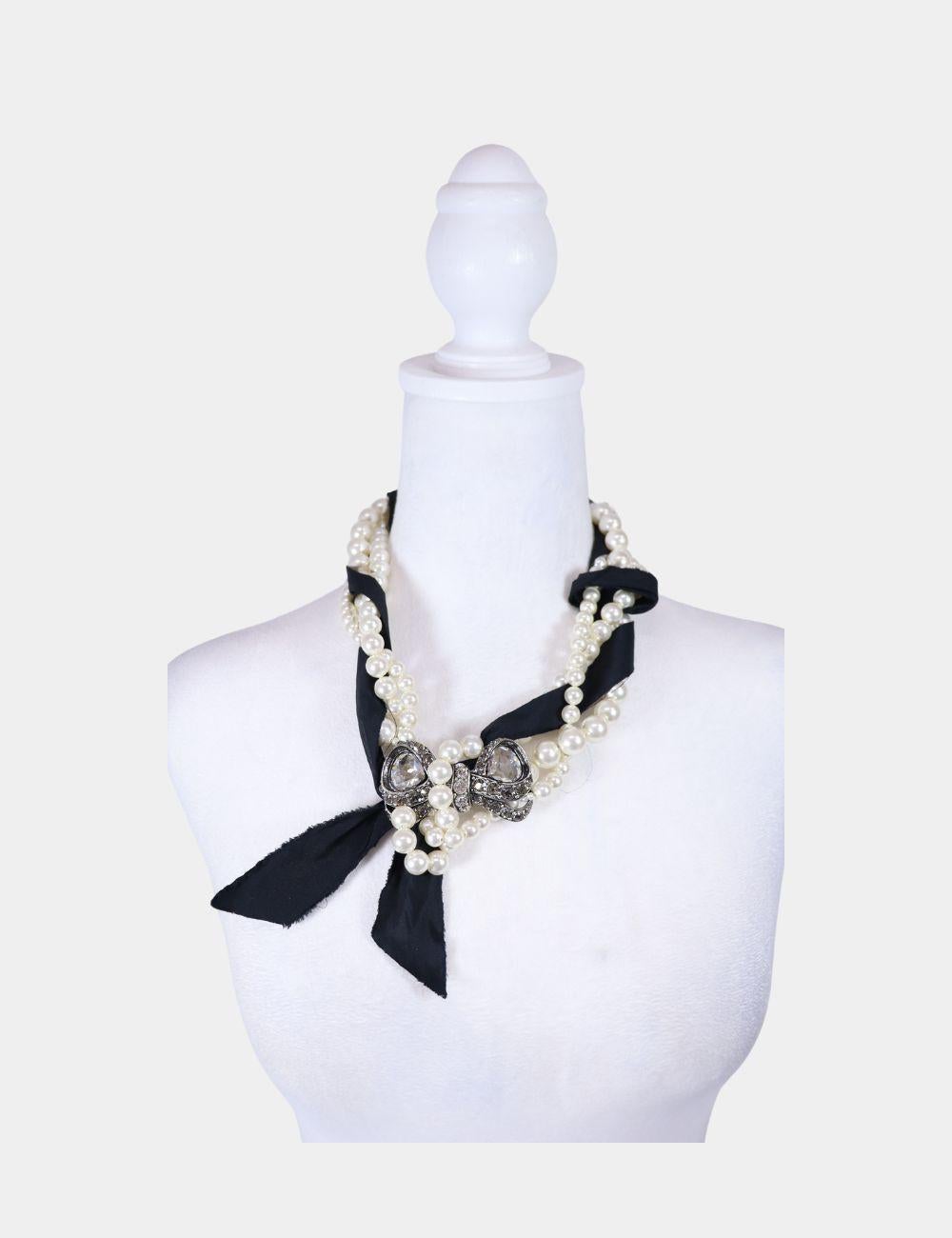 Lanvin Crystal and Faux Pearl Necklace, with an interwoven black ribbon, crystal embellished bow, and adjustable closure.

Material: Metal, Crystal and Faux Pearl
Length: 46-56cm
Condition: Good
* Includes Box
