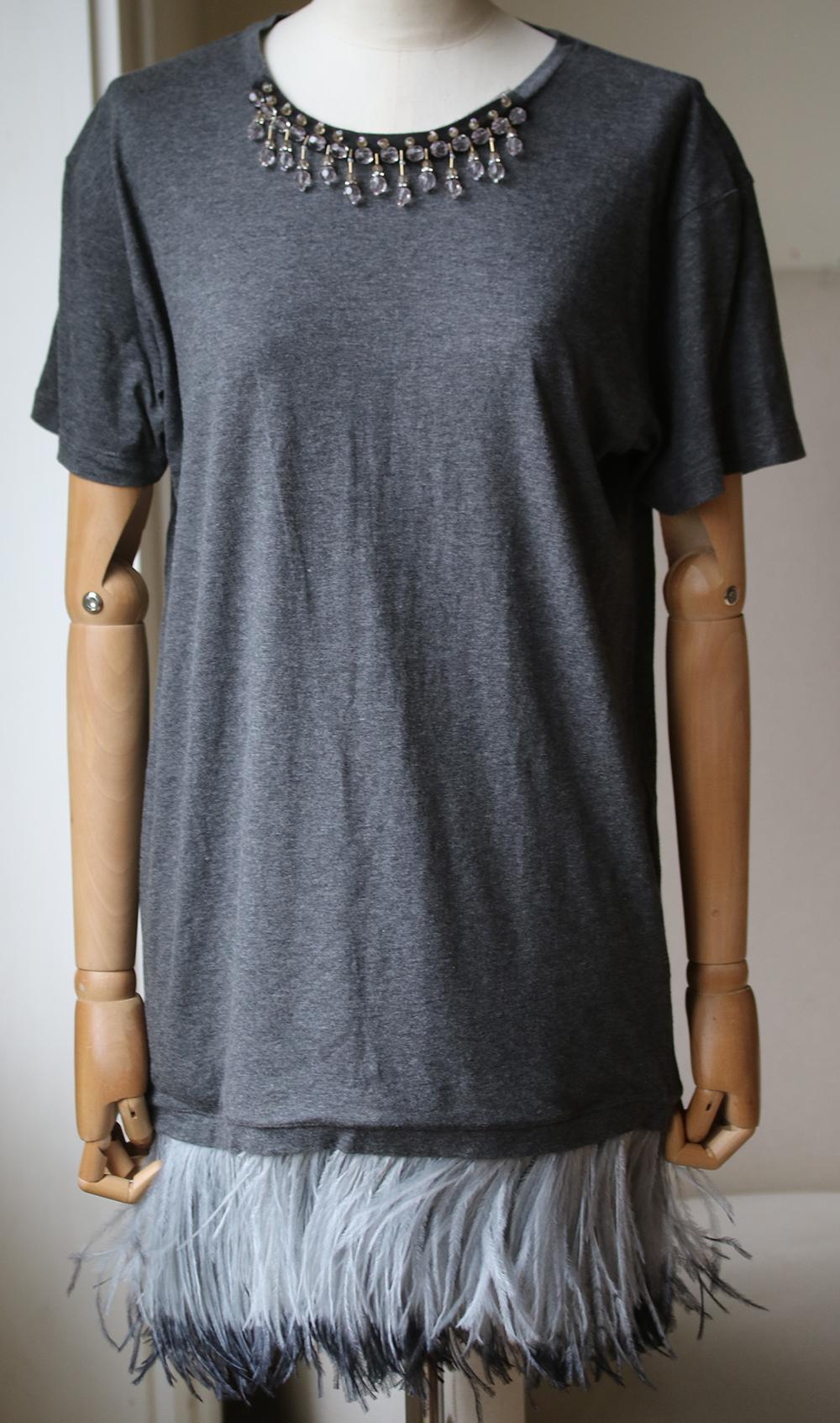 Cotton T-shirt featuring a round neck, short sleeves, embellishments at the neck and a feather detailed hem. 100% softest Ostrich feathers from South Africa. 60% Cotton, 40% Viscose. Colour: grey.

Size: One Size

Condition: New with tags. 