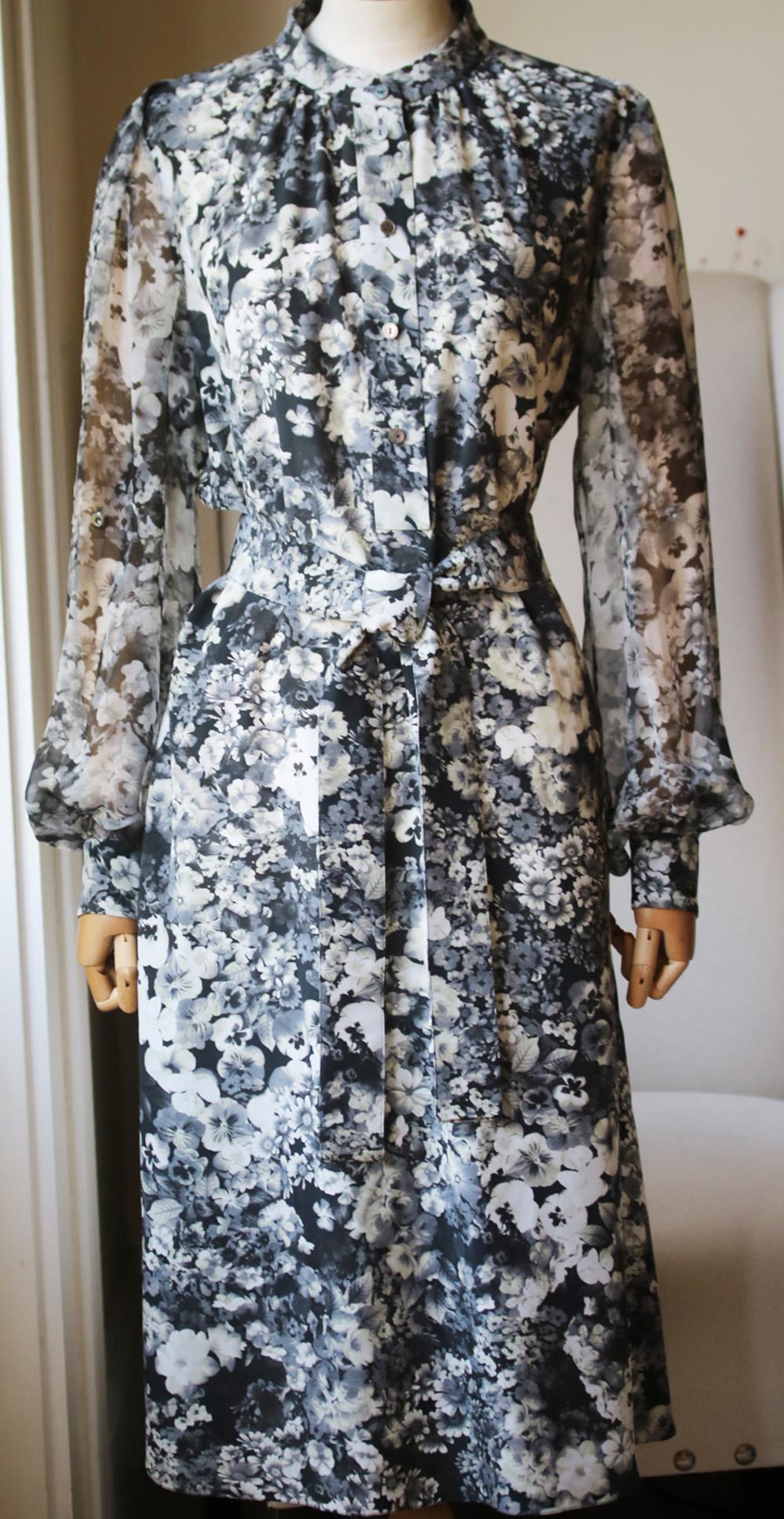 Grey and white silk flared floral print dress from Lanvin. Featuring a band collar, a front button placket, bell sleeves, button cuffs, a tie waist. Flared skirt and a back inverted pleat. Grey and black silk-chiffon. Button fastening. 100% Silk.