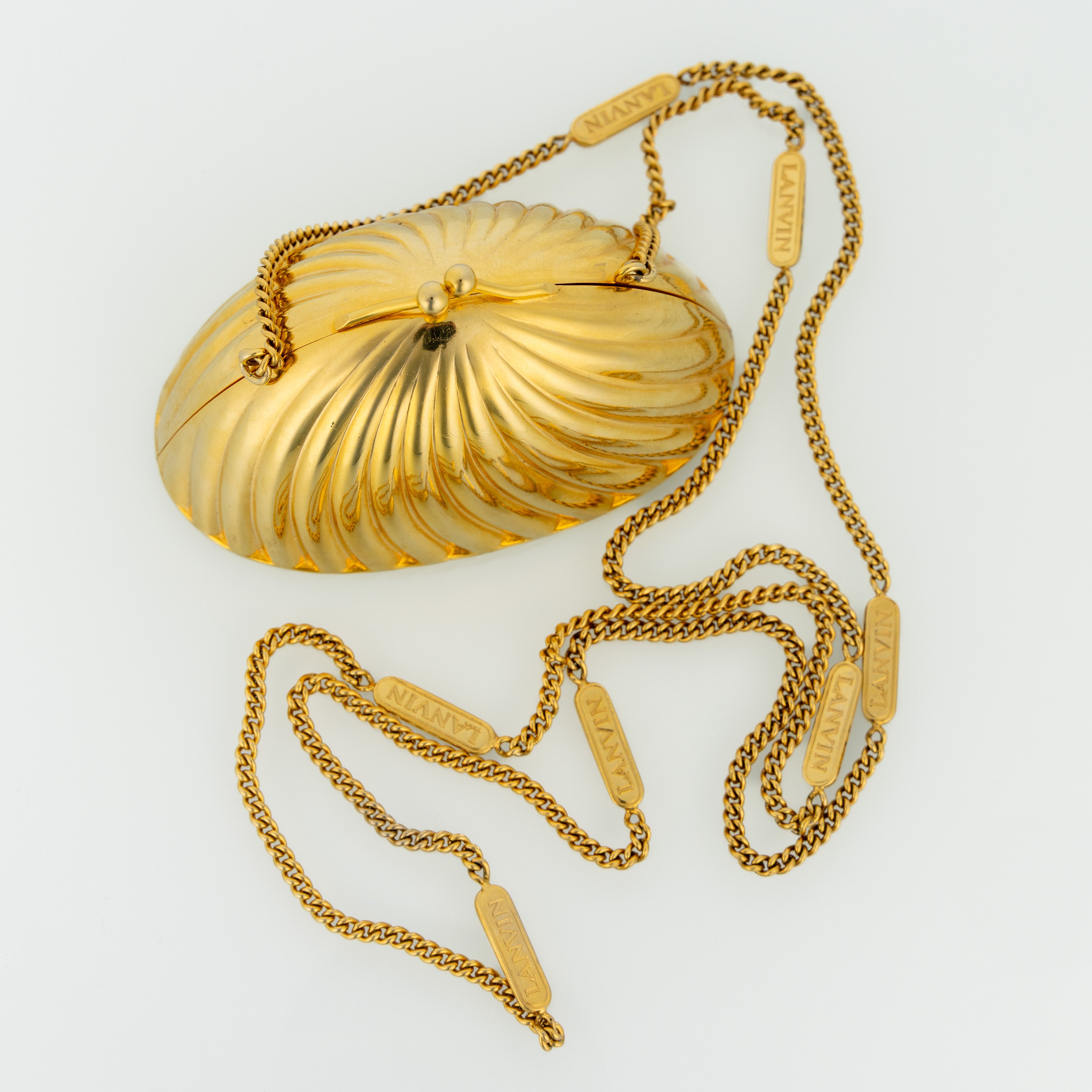 Borsa da sera minaudière Lanvin vintage in conchiglia color oro, realizzata in Italia con un design scultoreo a coste che ricorda una conchiglia Art Déco. La superficie in metallo dorato lucido cattura magnificamente la luce, creando un effetto