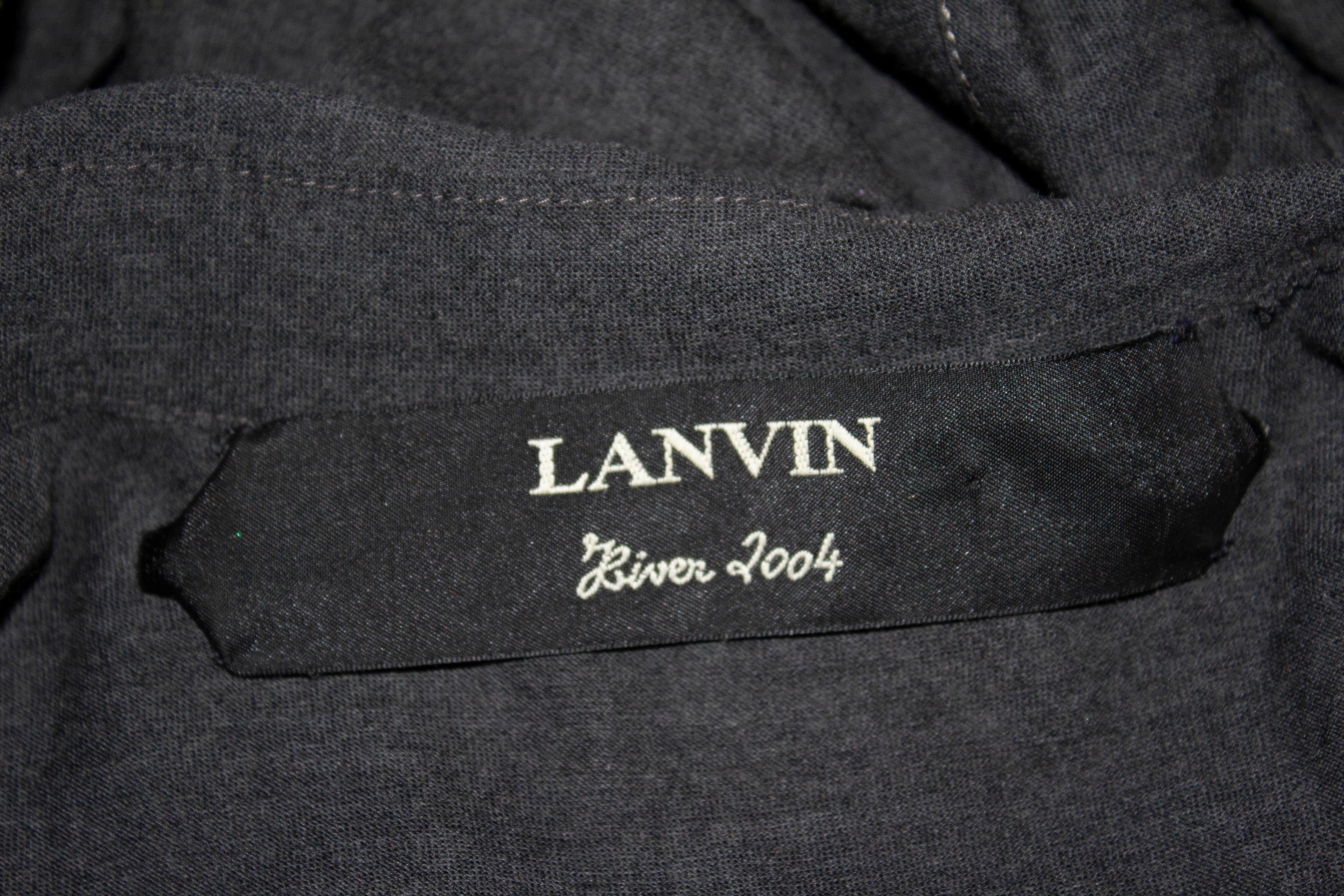 Une robe chemise chic en laine grise par Lanvin, hiver 2004. La robe se ferme sur le devant avec une ouverture à boutons-pression, possède une ceinture en tissu et des décorations sur le devant et le dos. 
Taille 38, Poitrine 38'', longueur 40''