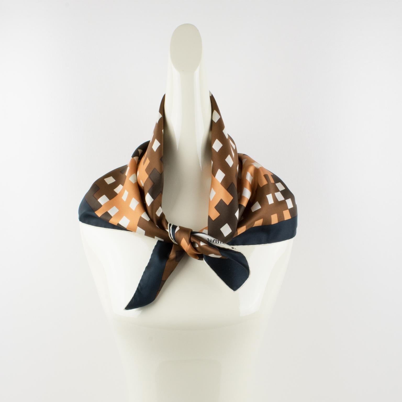 This elegant silk scarf by Lanvin Paris features a typical 1970s geometric print pattern. The combination of colors is bright and vibrant, with beige camel, beige cider, and brown spice over a white background with a hickory black border. The scarf