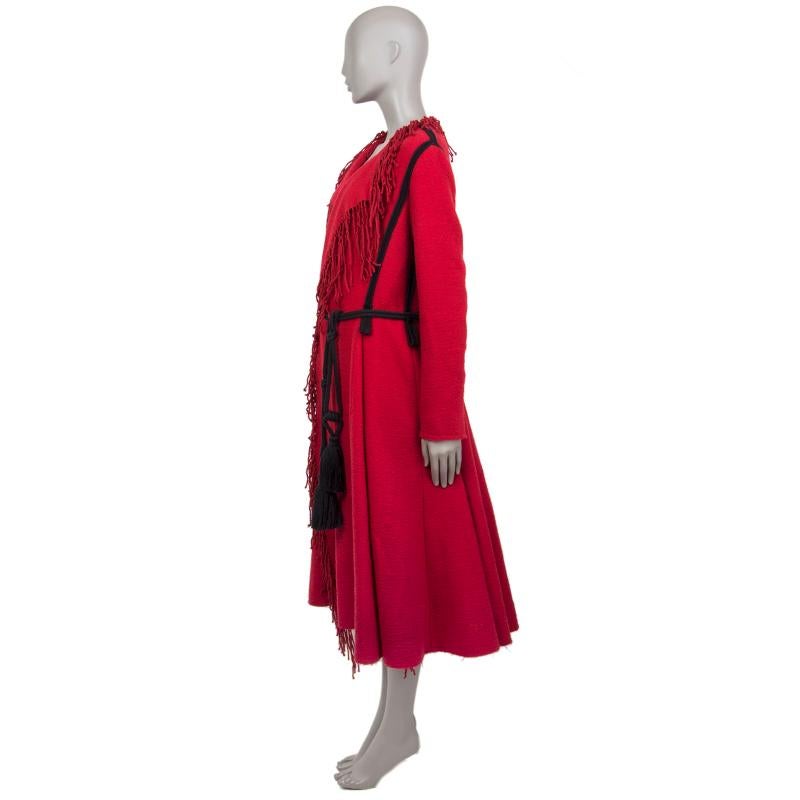 100% authentic Lanvin coat in red wool (88%) and nylon (12%). With fringe-edged draped collar, black strap trims, black belt loops, and two slit pockets on the sides. Unlined. Comes with belt strap in black cotton chord with tassel ends. Has been