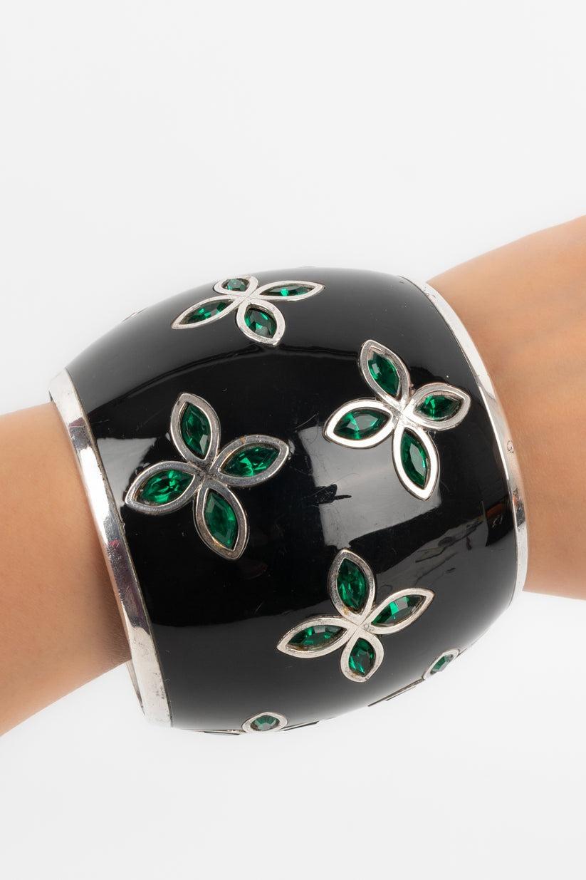 Lanvin - Rounded metal cuff bracelet with a black background and decorated with clovers and green stones. Not signed.

Additional information:
Condition: Good condition
Dimensions: Circumference: 20 cm - Diameter: 6.5 cm - Height: 7.7 cm

Seller