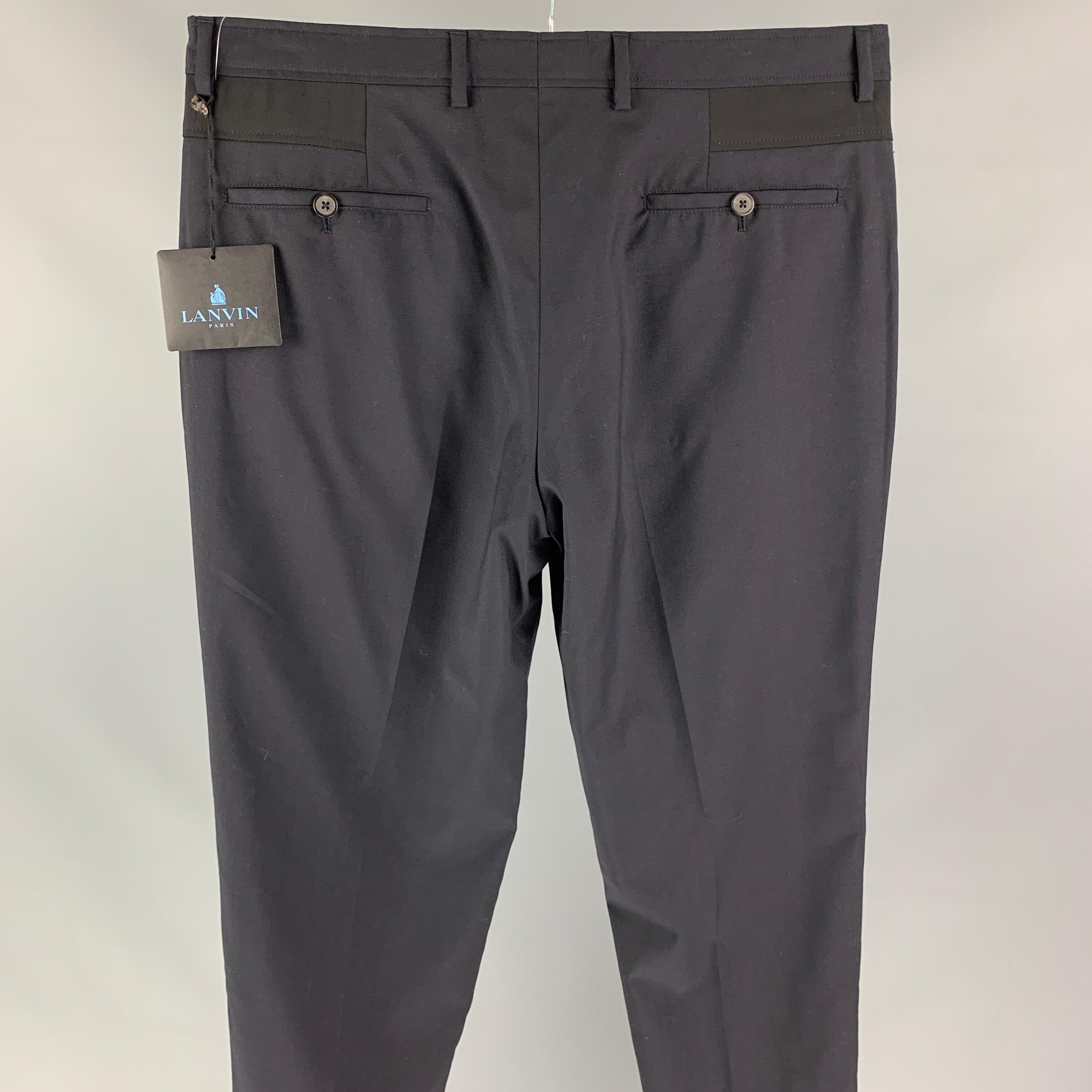 LANVIN dress pants comes in a navy wool featuring a slim fit, belt patch detail, front tab, and a zip fly closure. 

New With Tags. 
Marked: 50
Original Retail Price: $695.00

Measurements:

Waist: 34 in.
Rise: 9.5 in.
Inseam: 38 in. 