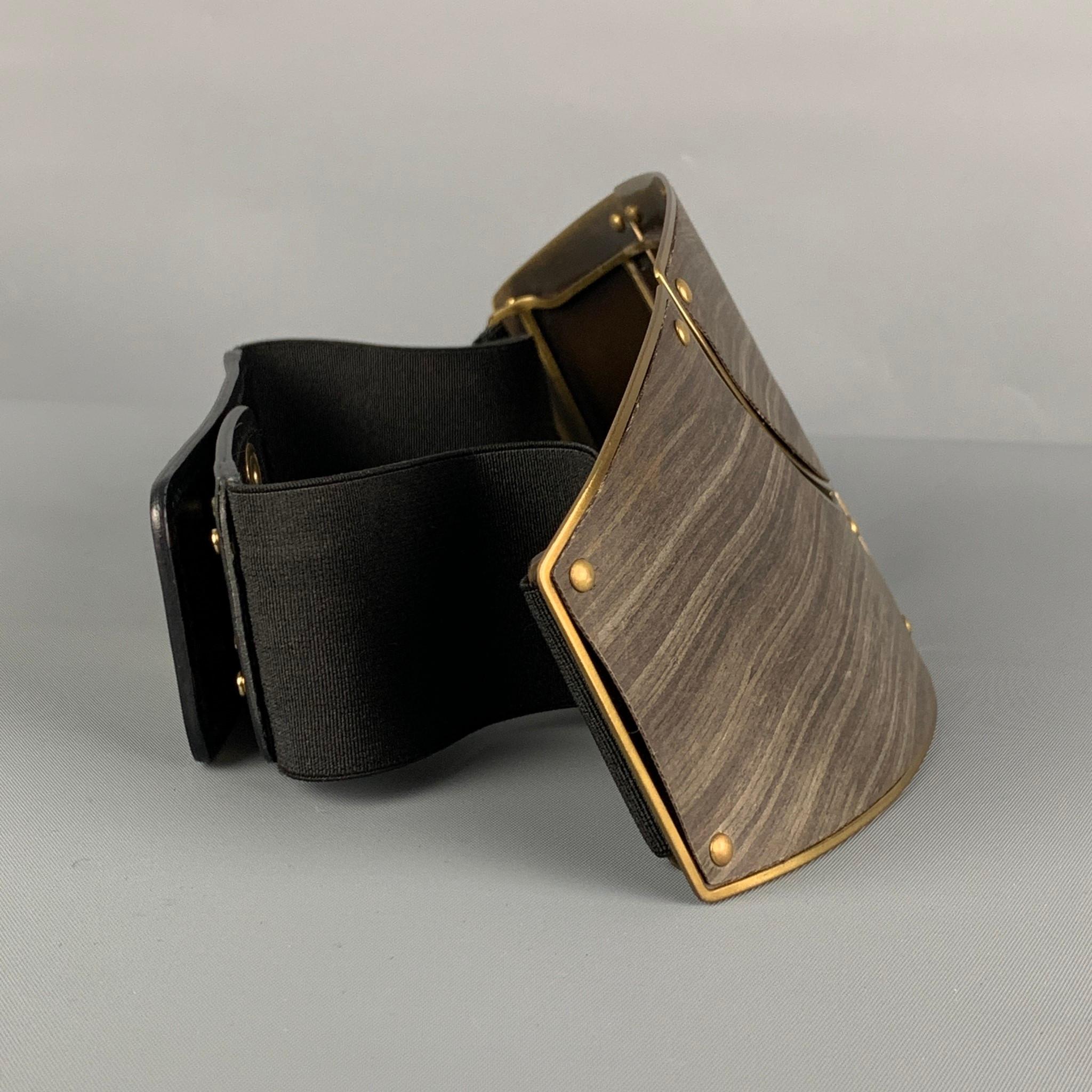 LANVIN belt comes in a brown metal featuring a large plate design, gold tone hardware, leather trim, black elastic strap, and a snap button closure. Made in Italy. 

Very Good Pre-Owned Condition.
Marked: S
Original Retail Price: $1,565.00

Length: