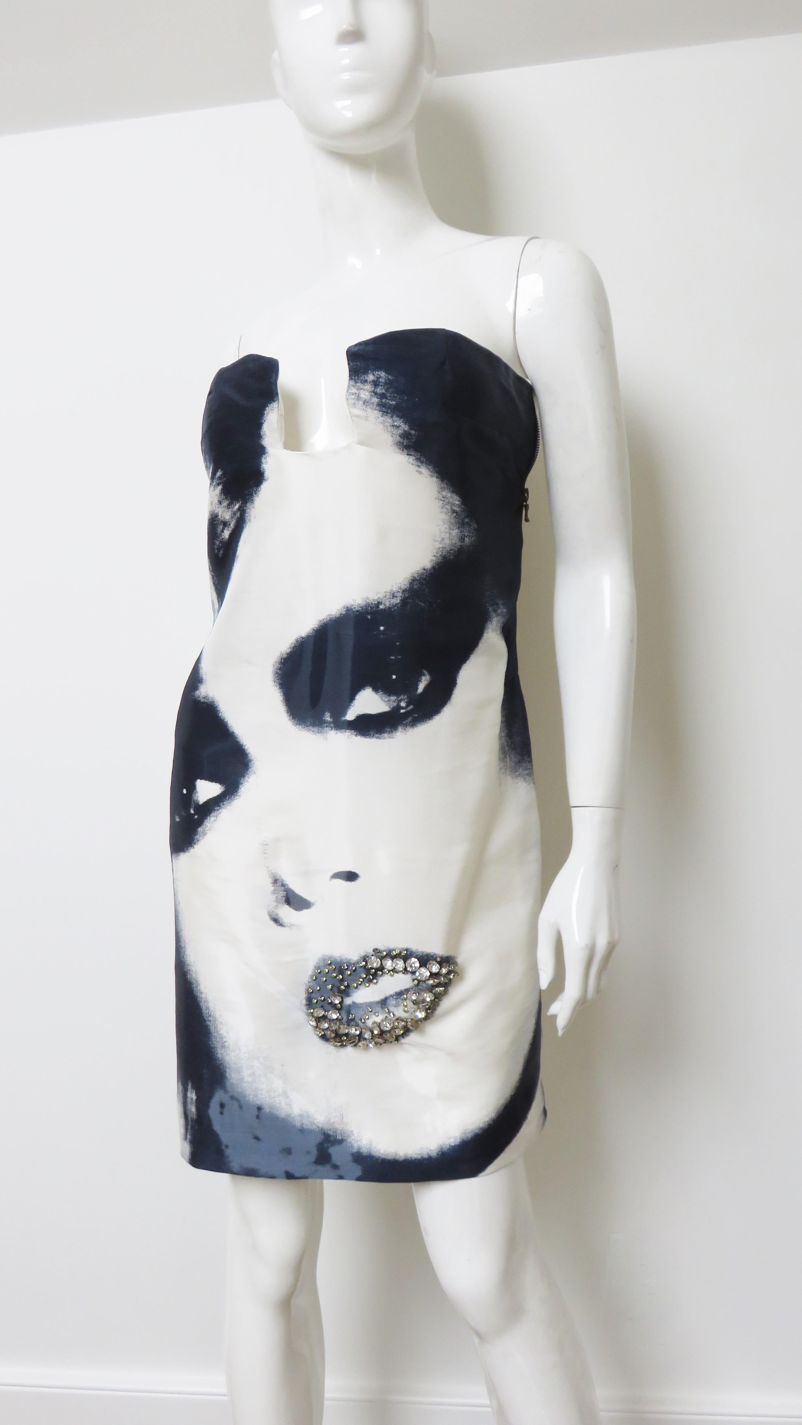 A stunning strapless black and white silk dress with a face on front by Alber Elbaz for Lanvin. It is strapless with a square center front cut out at the bust, an inner boned corset and strap to secure the dress and a fabulous large face print on