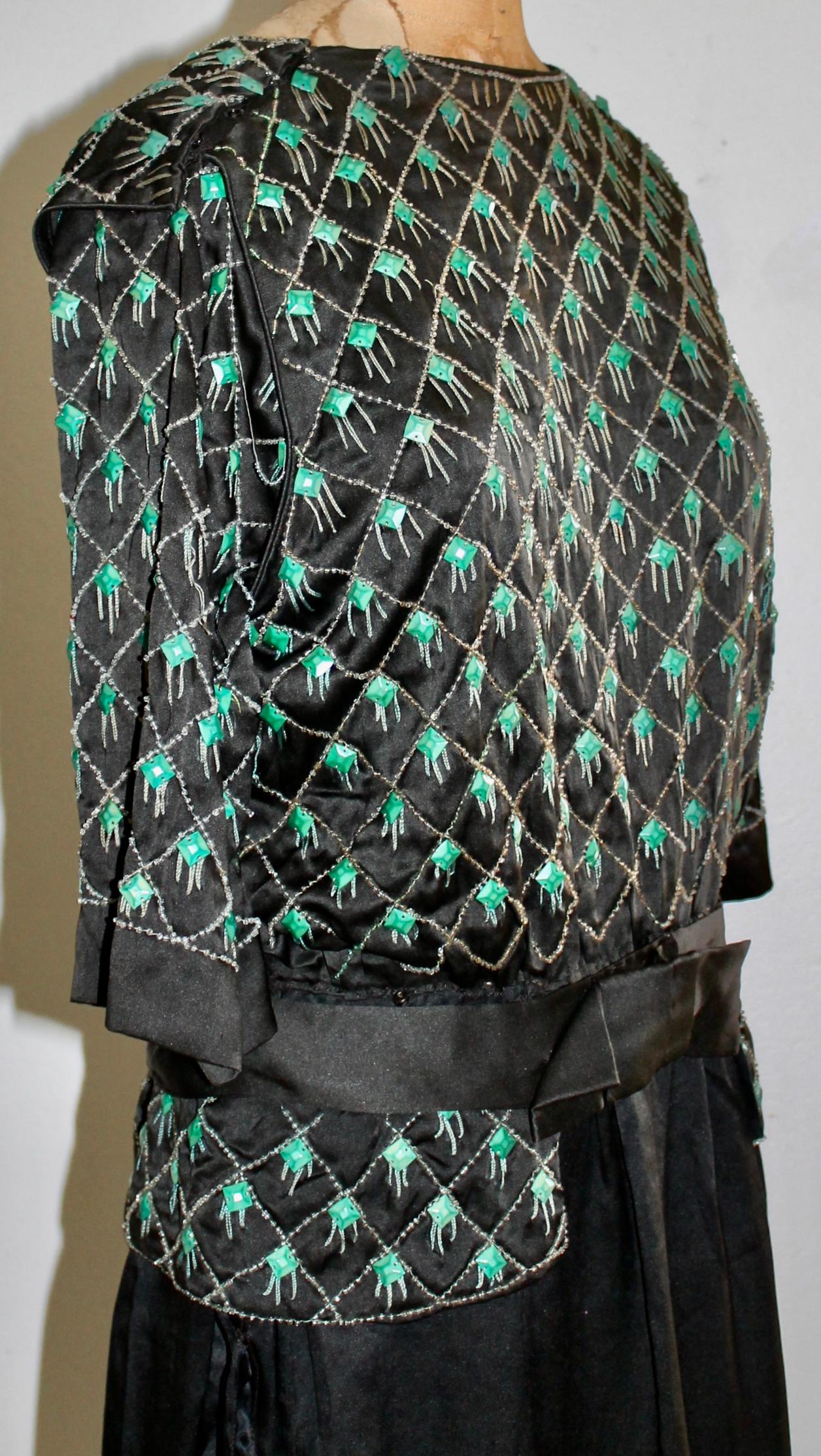 An unlabeled deco period black silk crepe dress, geometrically embroidered  with silver threads,  green plastic squares  and faux diamonds, in the style of Lanvin. A museum piece (wearable only with a restored lining.) appx an EU 36.