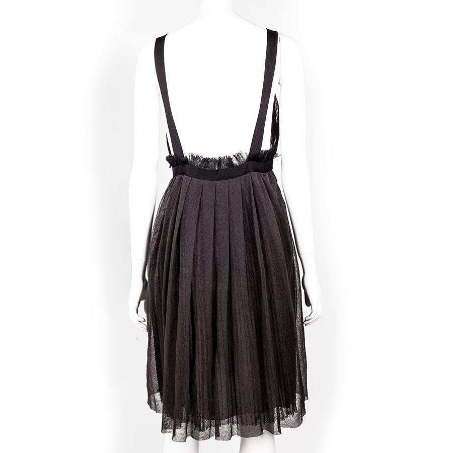 Straps in anthracite woven polyester, size 40 FR.
Lined with beige silk, decorated with a fabric rose, pleated, zipped on the left side. Black woven polyester petticoat visible on the back and bottom of the dress (see photo). Beige lining. Made in