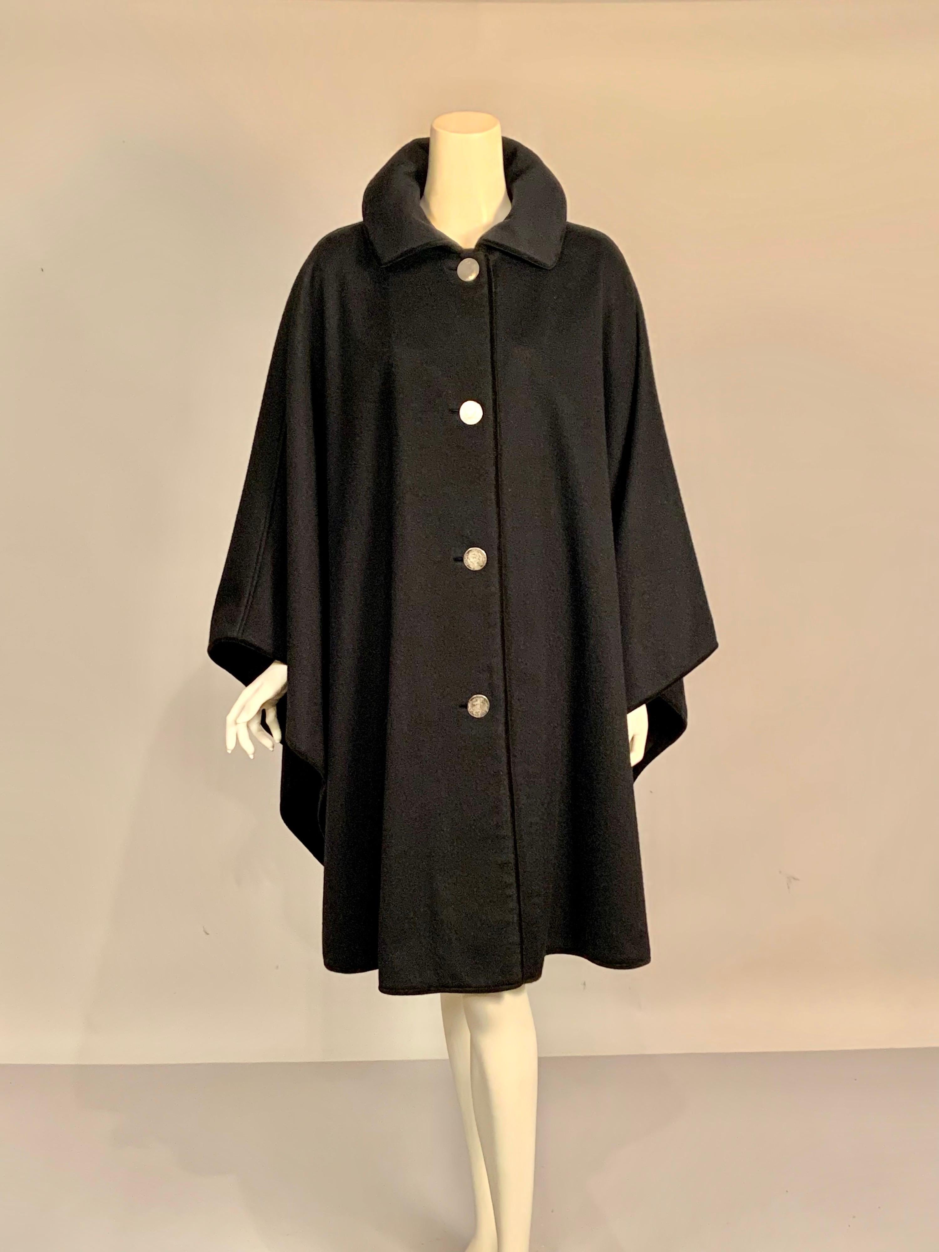 Soft & supple black wool drapes beautifully over the body, flattering every size.   This classic cape was designed by Lanz of Austria in the mid 20th century.  All of the edges are finished with brown velvet and the four silver buttons appear to be