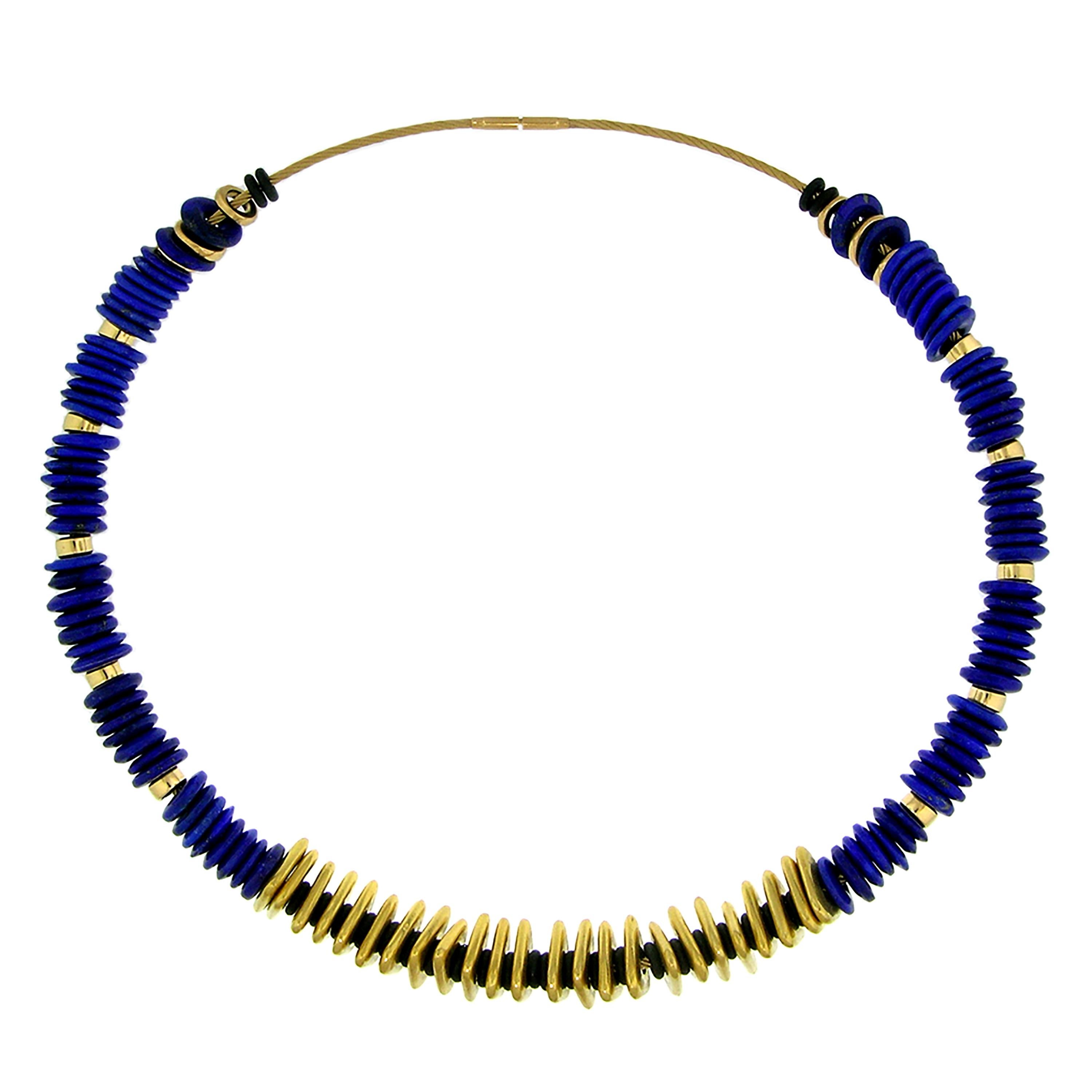 This gemstone beaded necklace features exquisitely made, knife-edged lapis beads paired with an abundance of 20kt handmade gold triangles and unexpectedly delightful black neoprene spacers.

This whimsically conceived necklace allows for