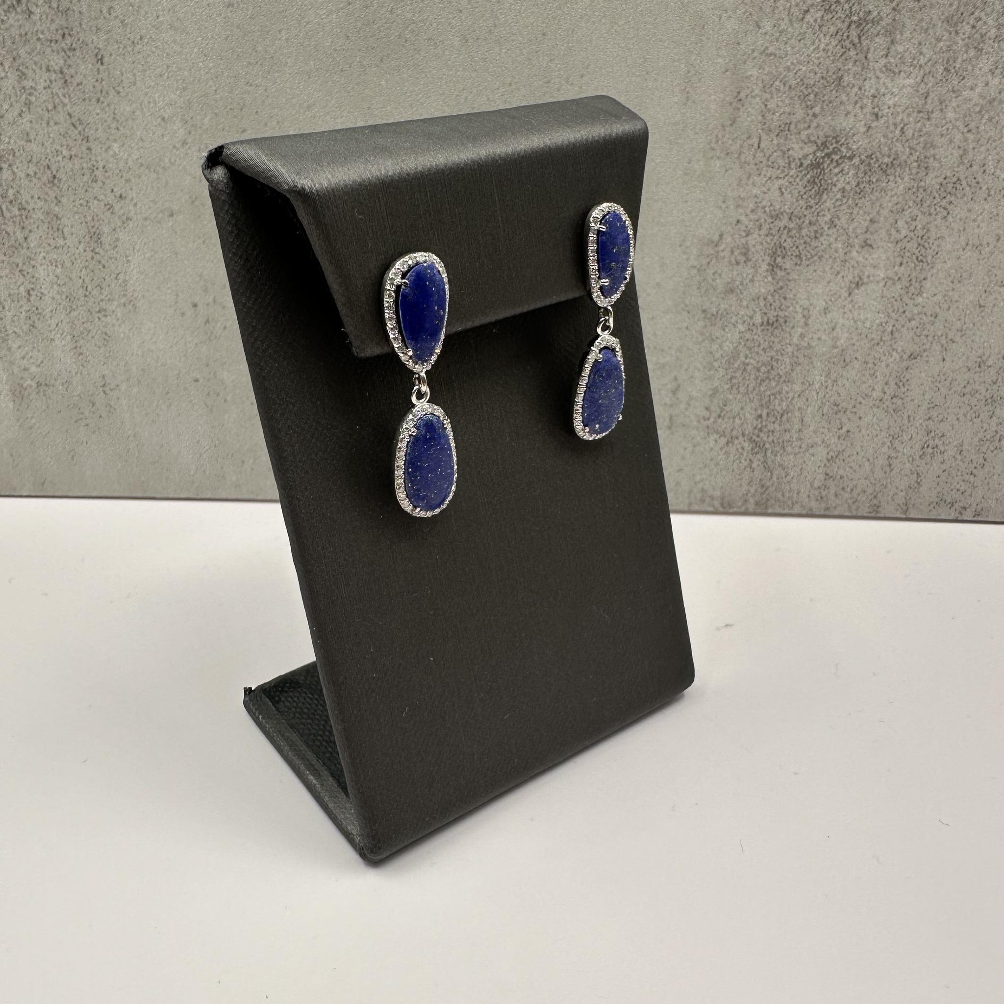 These striking Lapis and Diamond Drop Earrings in 14kt White Gold feature 4 abstract pieces of genuine lapis lazuli, complemented by approximately 0.50 carat total weight (ctw) of natural GH SI2-I1 eye clean round diamonds. The combination of the
