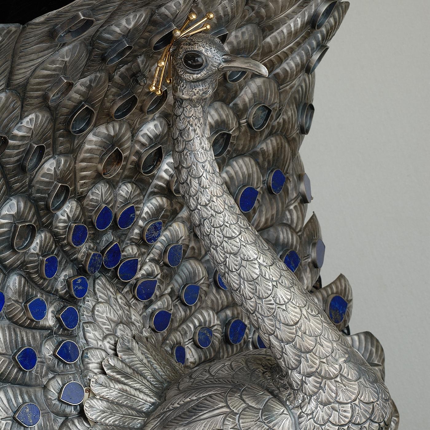 This piece is not merely a table but a work of art. A large, smooth black tabletop rests on what is more a sculpture than a table base formed by two back-to-back peacocks in antiqued silver and with blue lapis used as eyespots on the wings. The