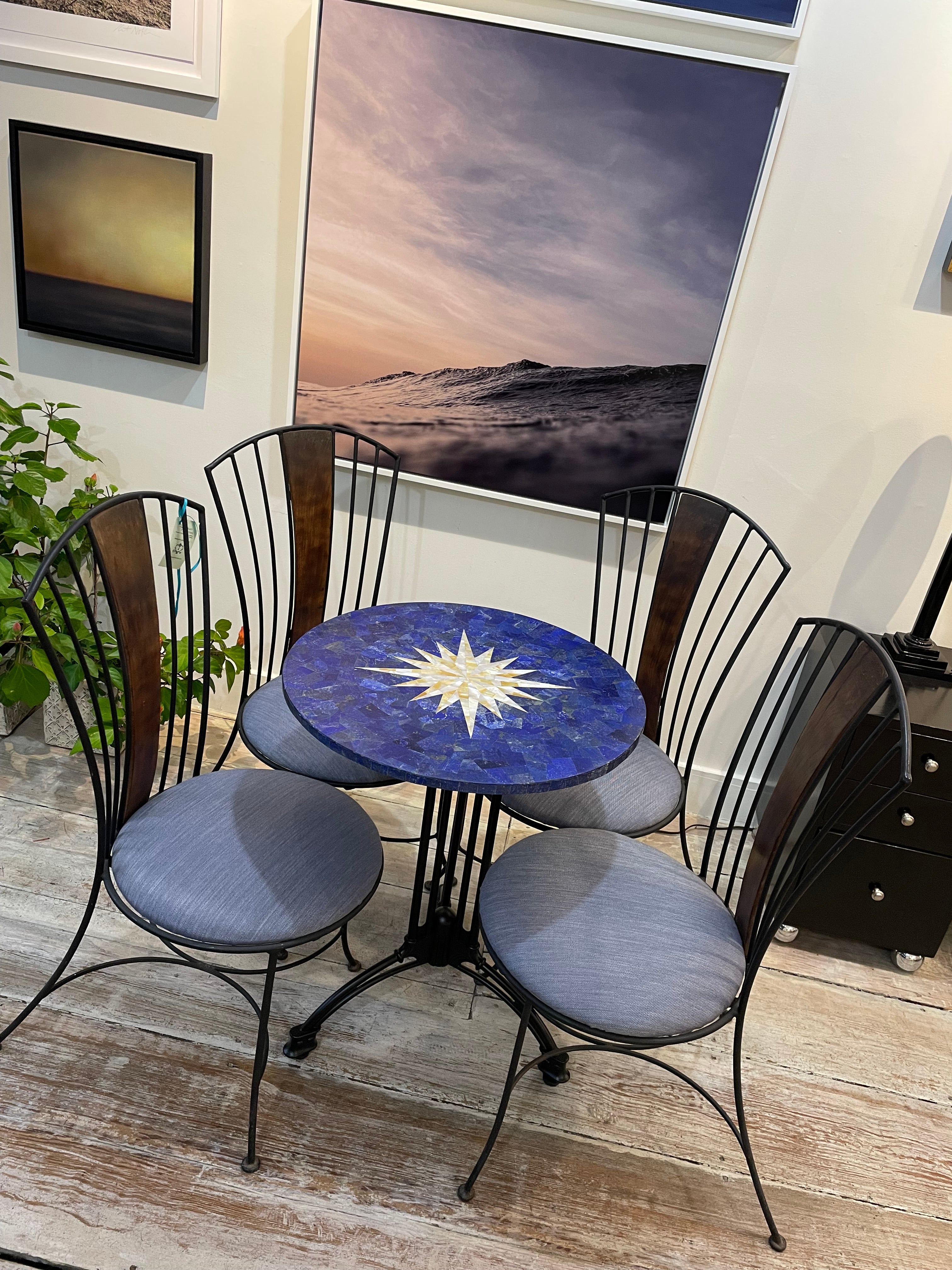 Lapis Lazuli pietra dura table top with mother of pearl inlay in a compass rose motif. Sits on an black aluminum base and features 4 iron chairs with a center wood back. Cushions are new blue sunbrella fabric. Great to use on a patio, porch,
