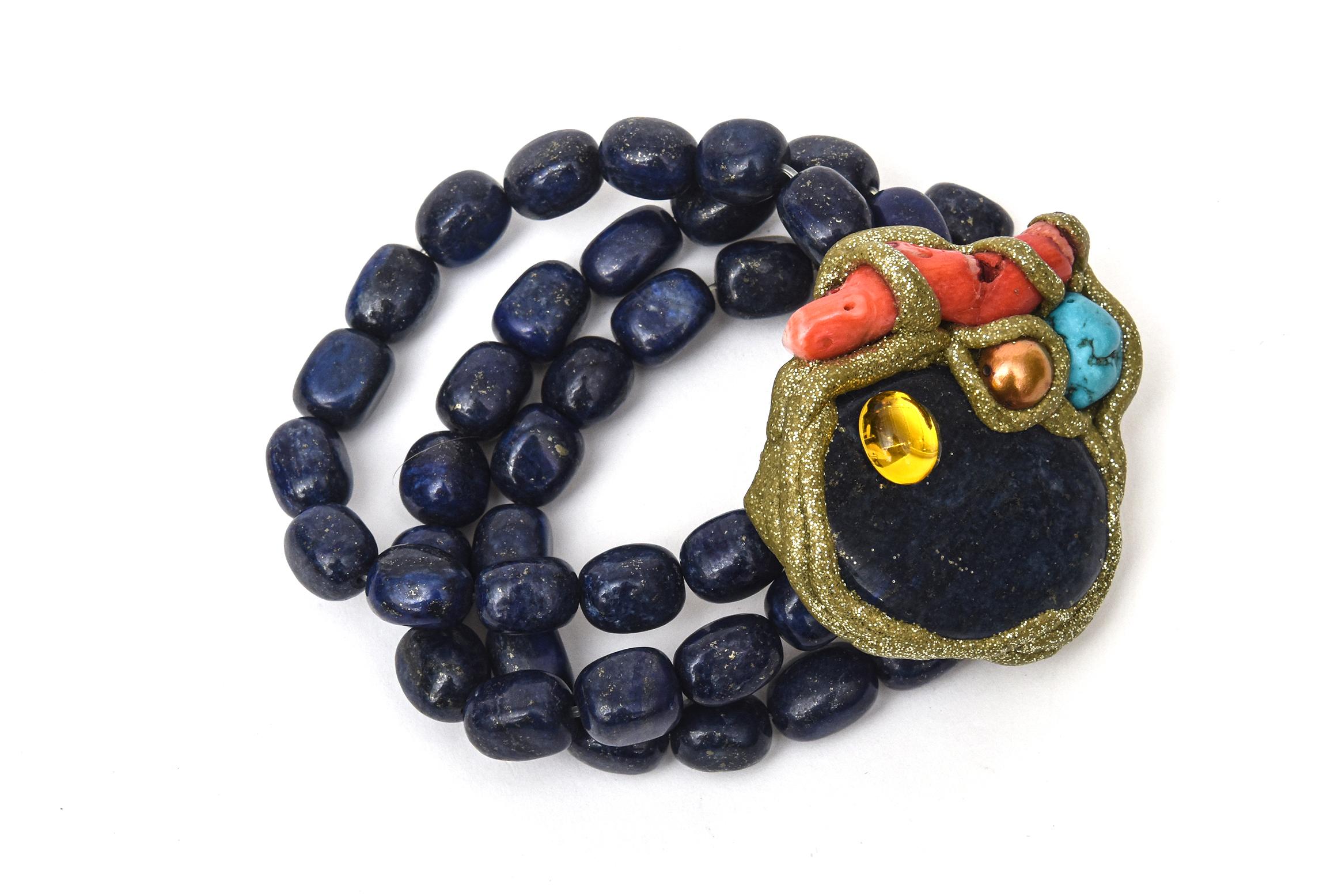 This gorgeous 3 strand hand wrought one of kind bracelet has the elements of lapis beads as the 3 strands with a center medallion of lapis surrounded with citrine, turquoise, coral and copper wrapped wth brass. The 3 strands of lapis stones are
