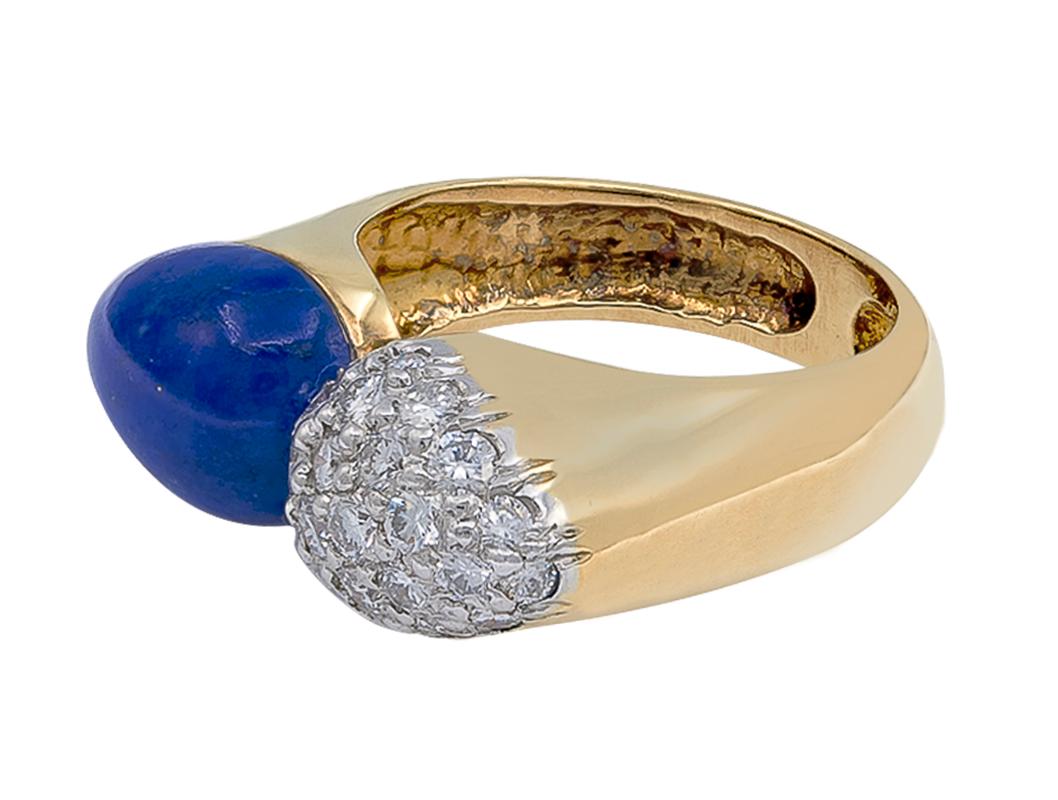 Cette bague moderne et chic est sertie d'un lapis-lazuli en forme de poire.  et 25 diamants taille brillant pesant environ un carat stylisés dans une monture Bombé. Contrairement à la conception habituelle du by-pass, les deux éléments qui composent