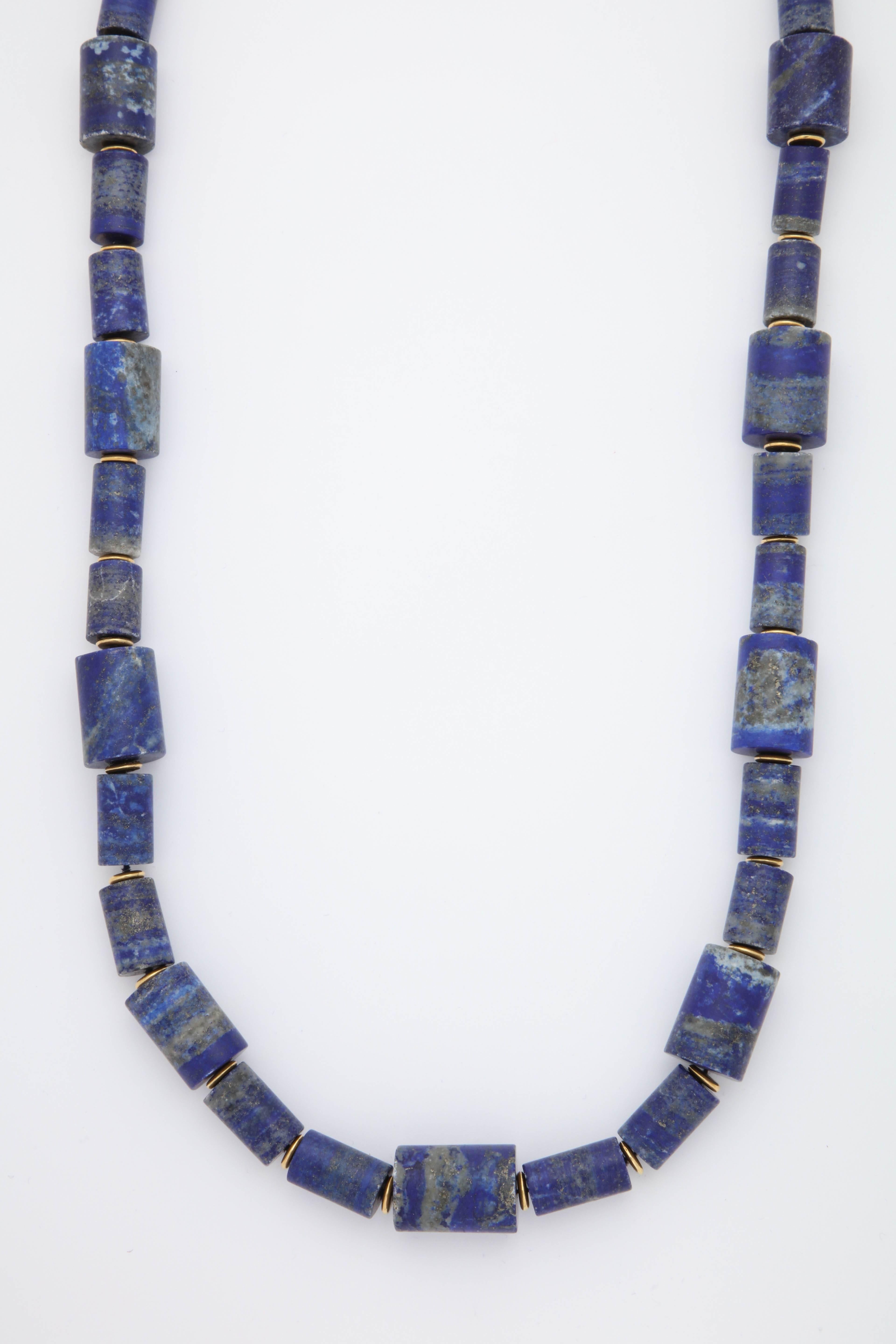 A necklace composed of alternating honed lapis lazuli barrel beads and 18kt yellow gold button beads.

Length: 38.50 inches