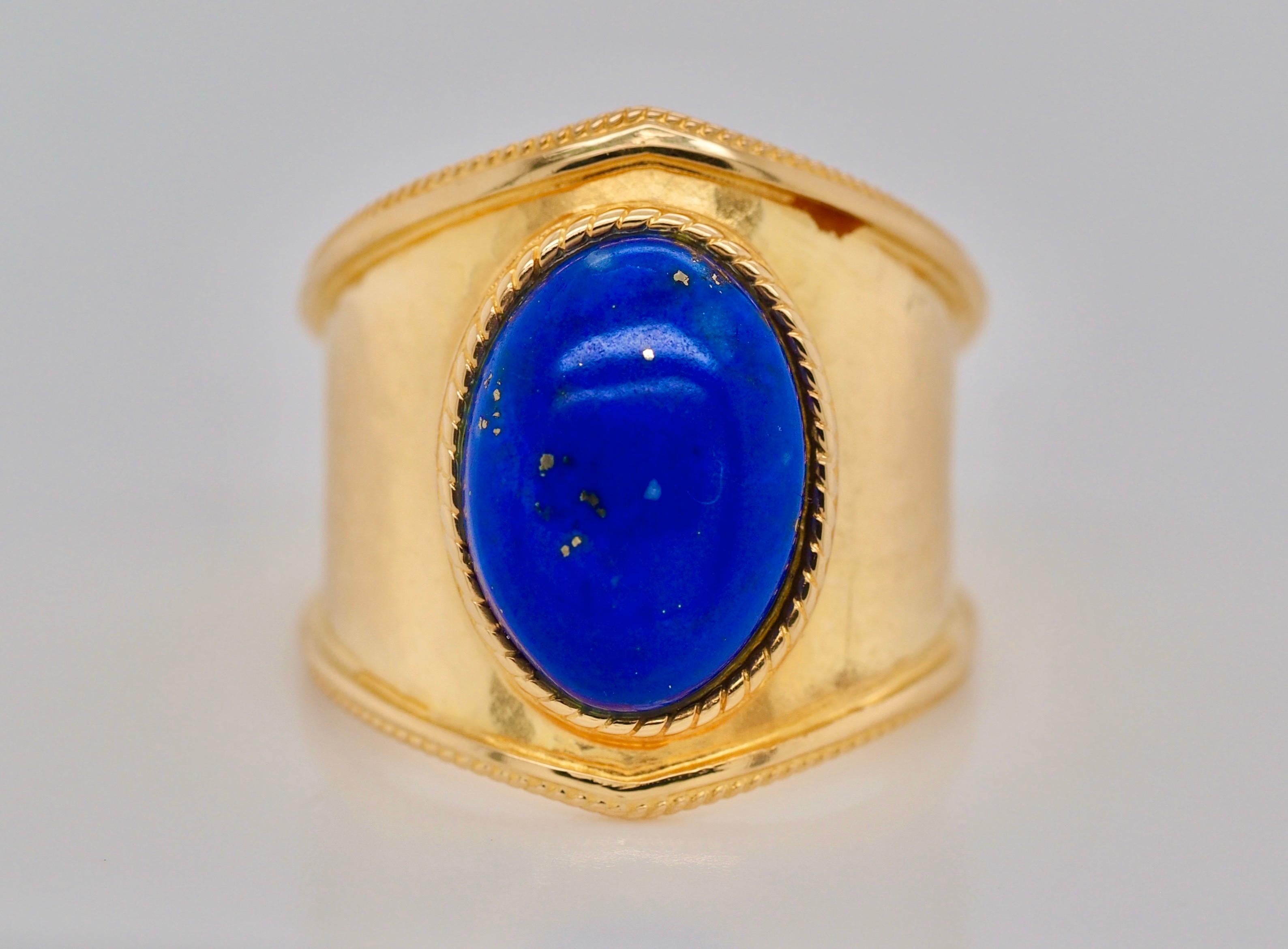Greek 1980s lapis lazuli gold ring band.  The Etruscan style design features a bezel-set lapis lazuli that is a radiant blue with visible golden flaked. The lapis is  bezel set on a wide and tapering 18-karat yellow gold ring band with a hammered