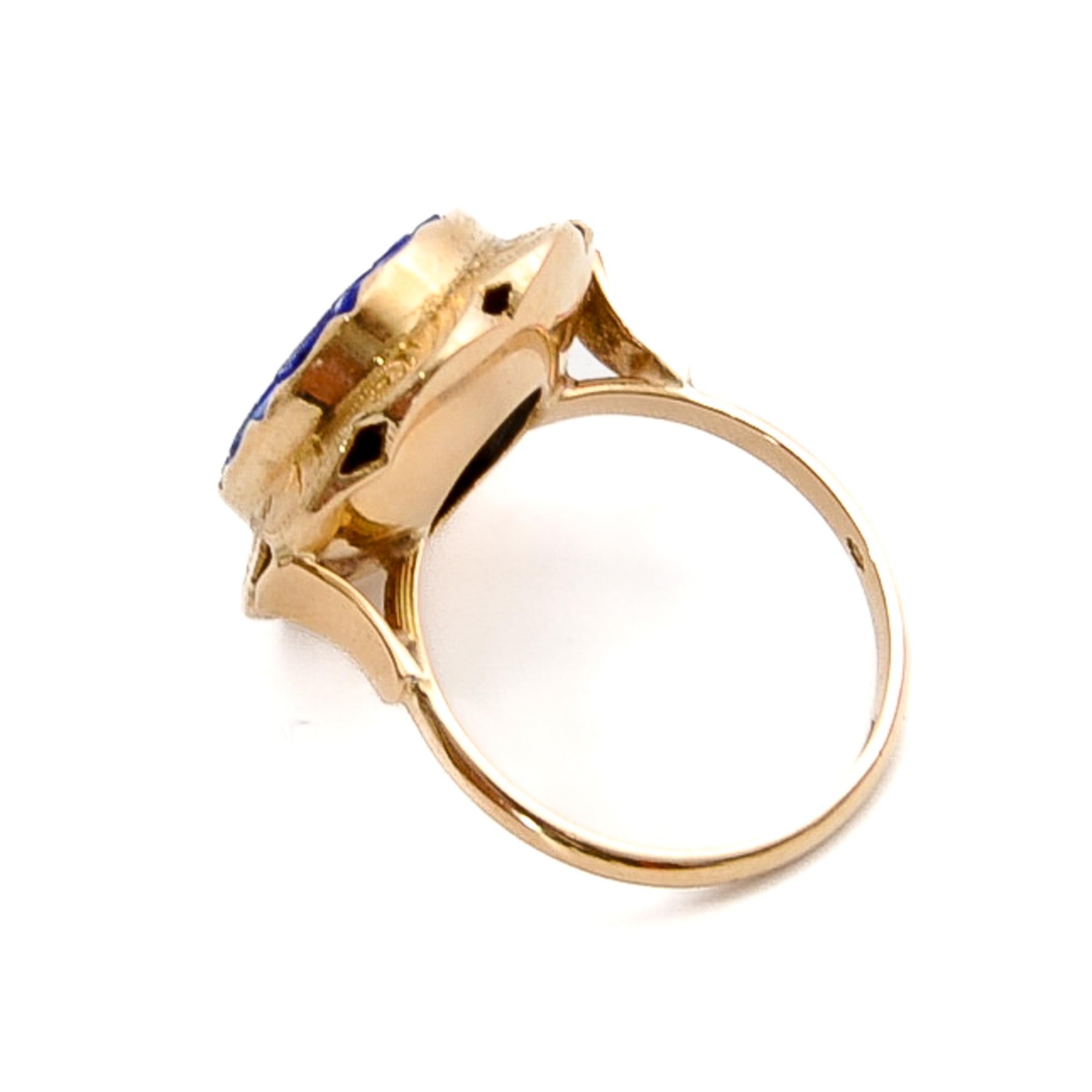 This is a vintage 14 karat yellow gold ring crafted with a beautiful carved lapis lazuli gemstone. The design creates this lovely engraved gold mounting of the ring. The edge of the mounting is oval-shaped and scalloped. The lapis has an amazing