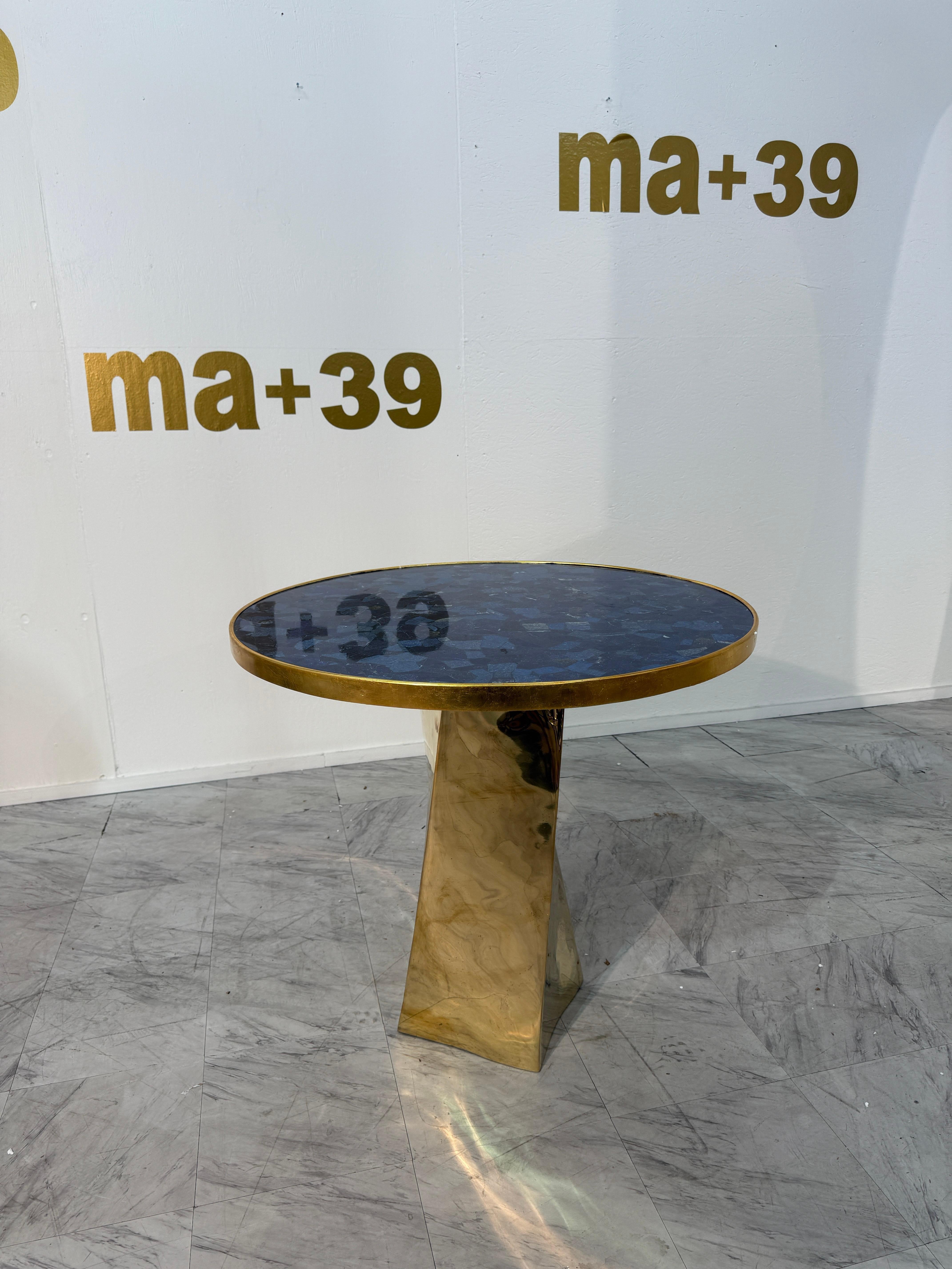 Dieser Tisch von Fonderia Artistica Ruocco ist ein außergewöhnlicher Ausdruck skulpturaler Handwerkskunst und erforscht die dynamische Spannung zwischen Geometrie und organischer Textur. Die runde Platte ist mit einem Mosaik aus tiefblauem Stein -