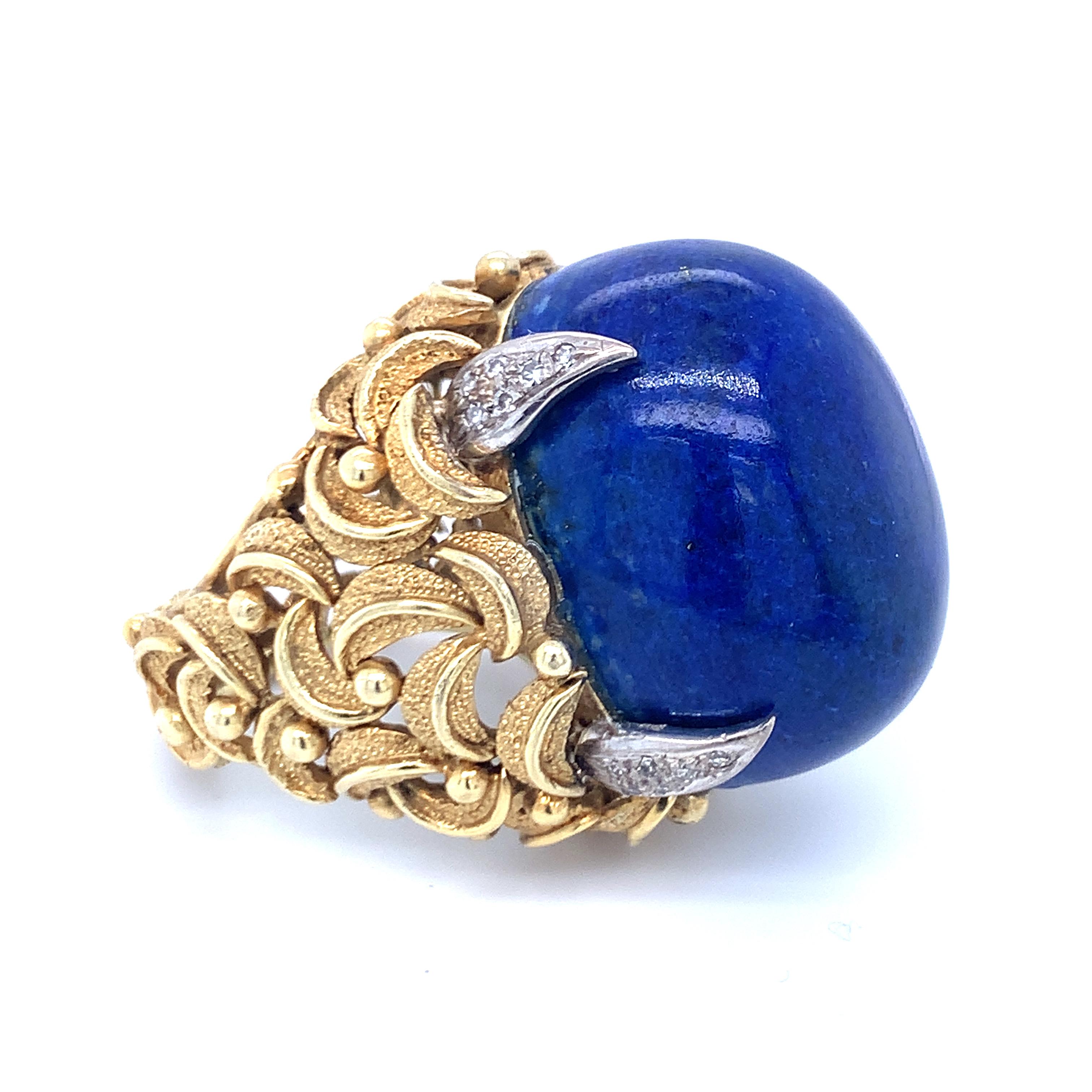 One lapiz lazuli and diamond 18K yellow gold ring with heavily textured gold finish centering one massive oval cabochon lapis stone measuring 28 x 20 x 15 mm. in size. The ring is further accented by 24 single round cut diamonds weighing 0.30 ct. in