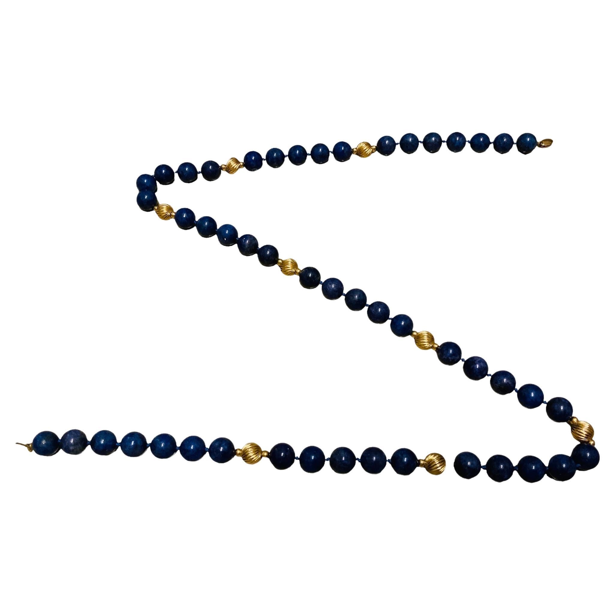 This is a Lapis lazuli and gold beads long necklace. It depicts a necklace made of round large Lapis lazuli spheres fasten on a string. It is adorned with large ribbed in spiral way gold beads that are also placed in the same way. Lapis lazuli beads