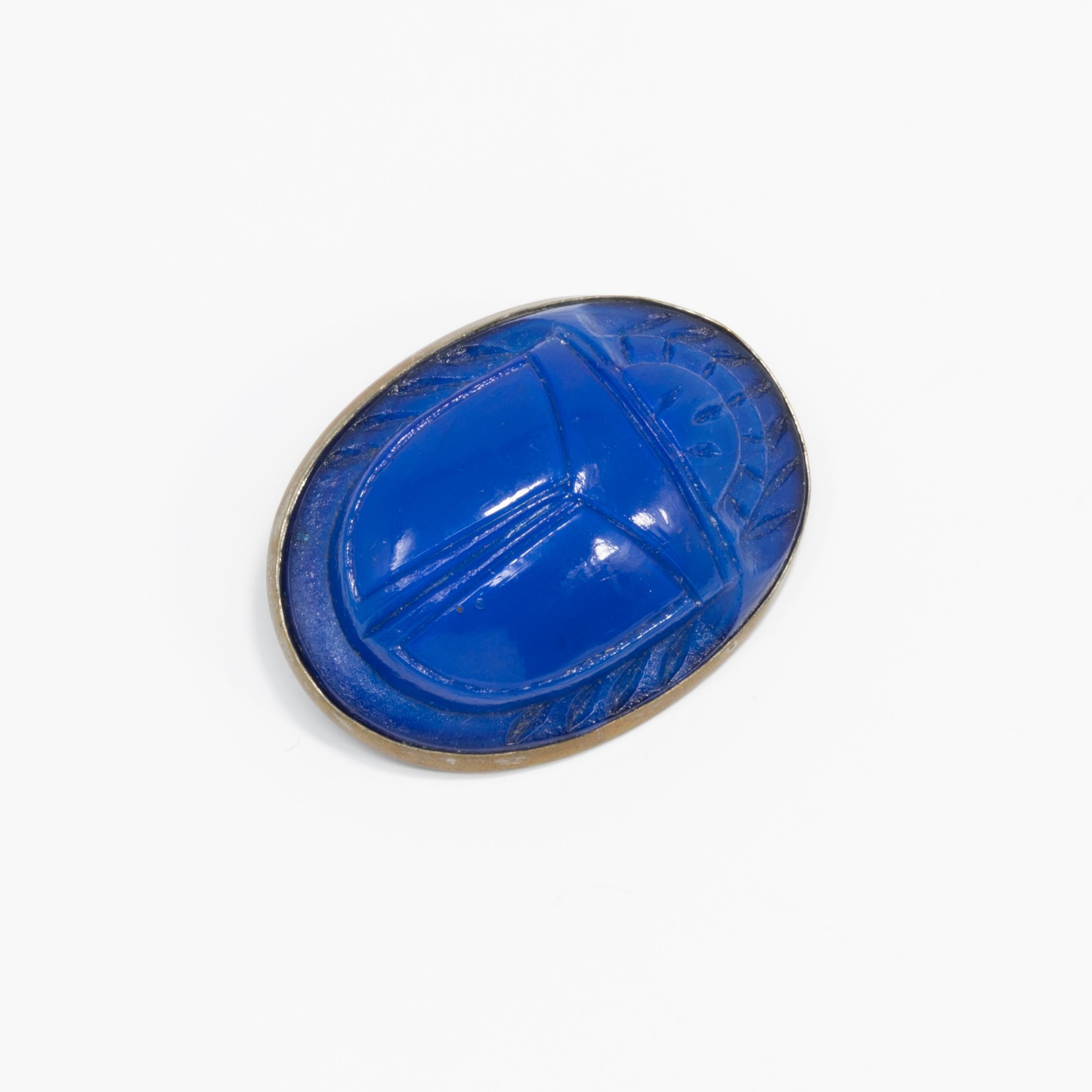A stylish deco pin, with a carved lapis lazuli scarab set in an oval bezel.

Dated early 1900s. 