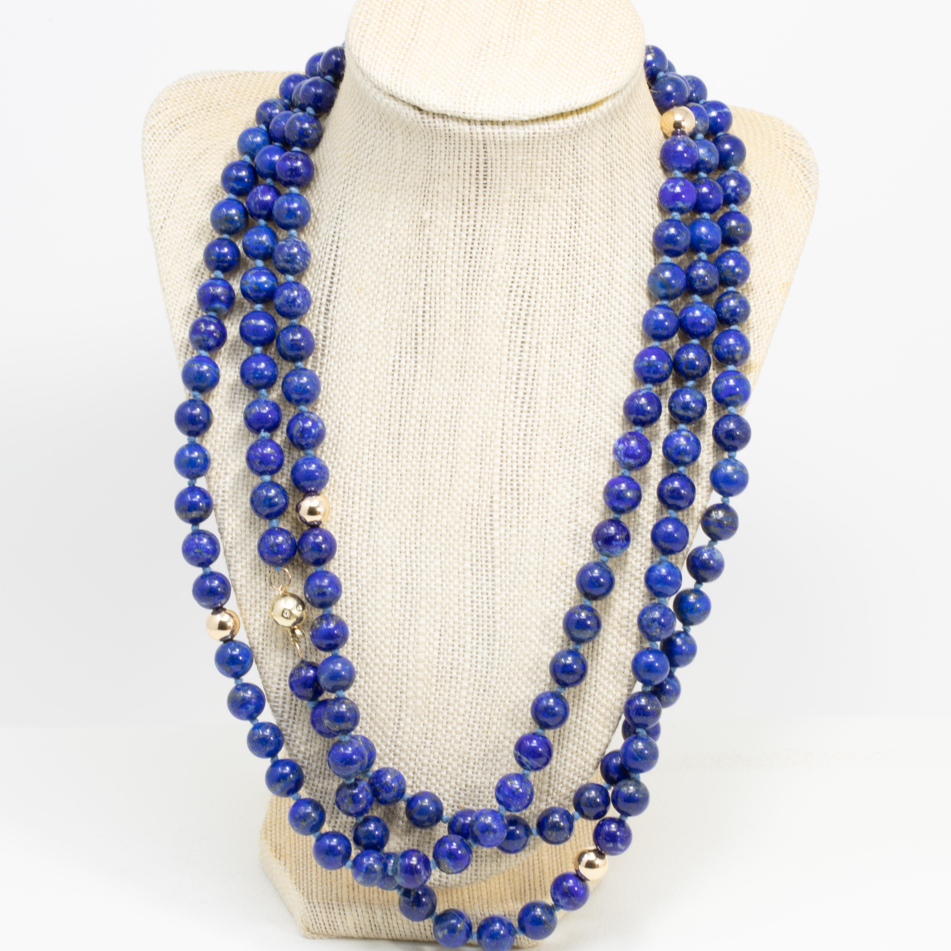 An exquisite genuine lapis lazuli bead necklace. Features a long strand of 10mm lapis lazuli beads accented with 14K gold beads. The 14 karat gold ball clasp is decorated with clear diamonds. A refined accessory fit for the most sophisticated