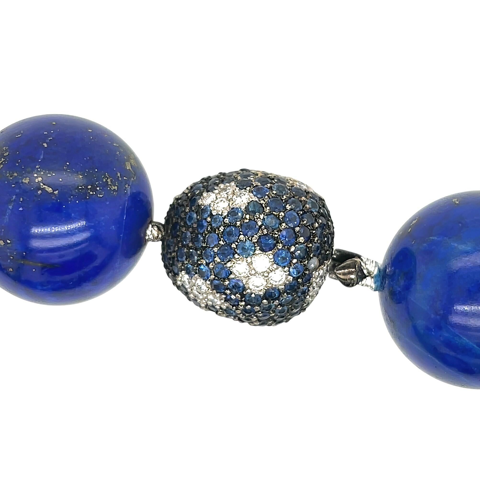 Una collana in oro 18 carati, lapislazzuli, zaffiri e diamanti.  Disegnato come un filo di circa 20 perle rotonde di lapislazzuli di circa 20,0 mm completate da una chiusura a forma di fagiolo con numerosi zaffiri rotondi sfaccettati intervallati da