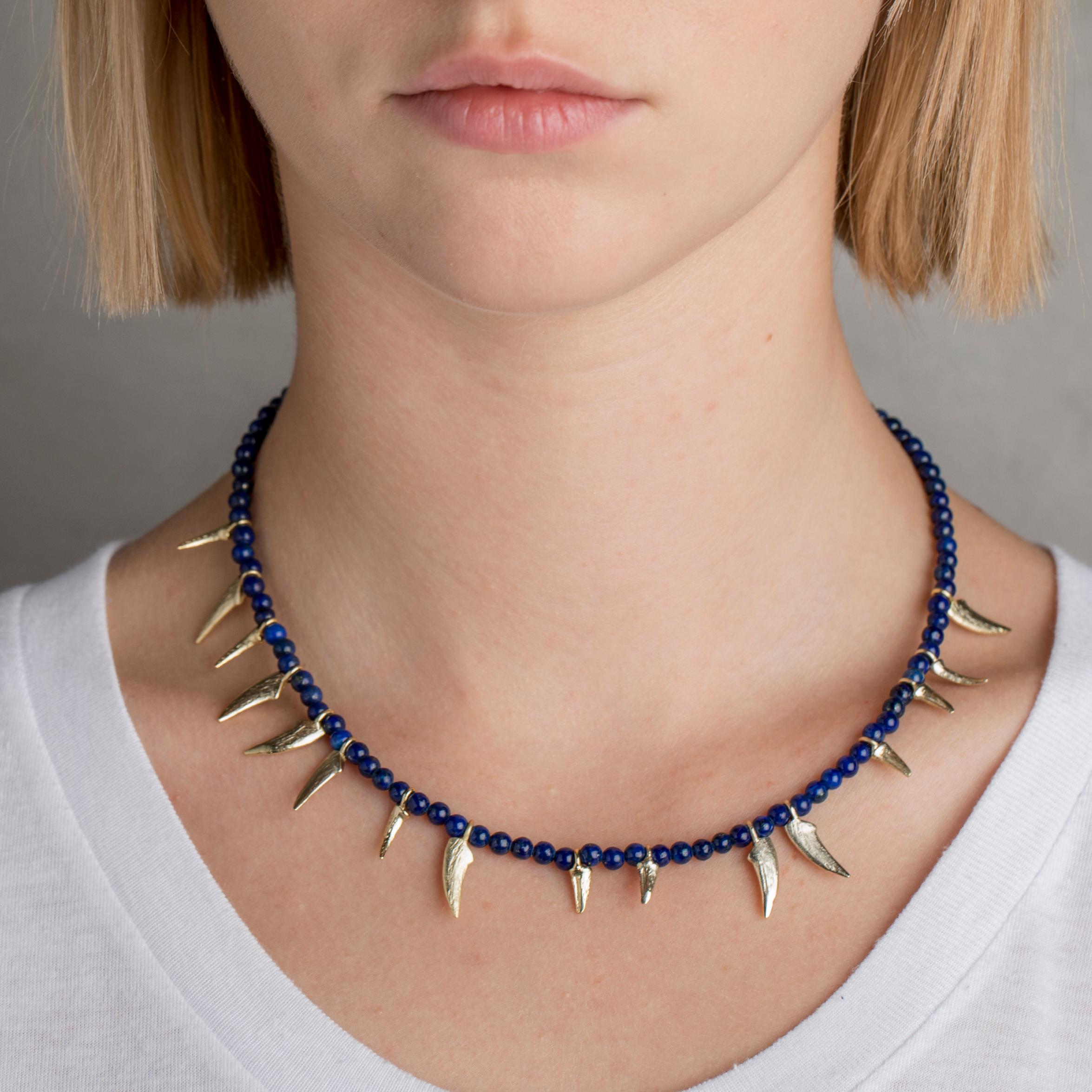  Iosselliani captures both edgy and bohemian look with this beaded necklace from its newest BE NOMAD Collection. The necklace features the iconic claw details hanging alternate from a strand of round shaped lapis lazuli beads.  The claws are brushed