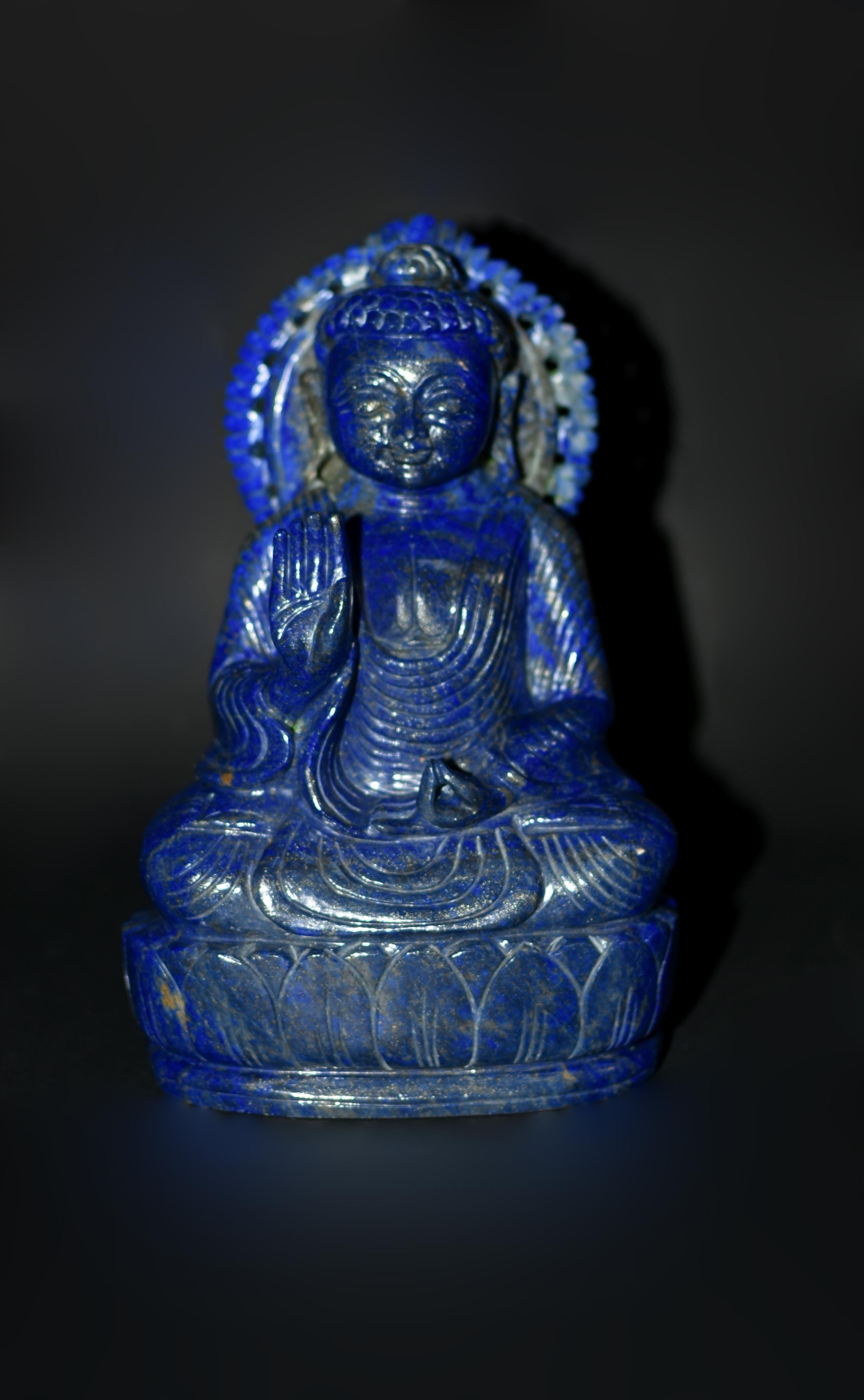 Finely carved from the highest grade natural lapis lazuli from Afghanistan, this 6-lb gemstone statue exudes an aura of peace and tranquility, portraying Shakyamuni, the historical Buddha. His round face, adorned with large downcast eyes and long