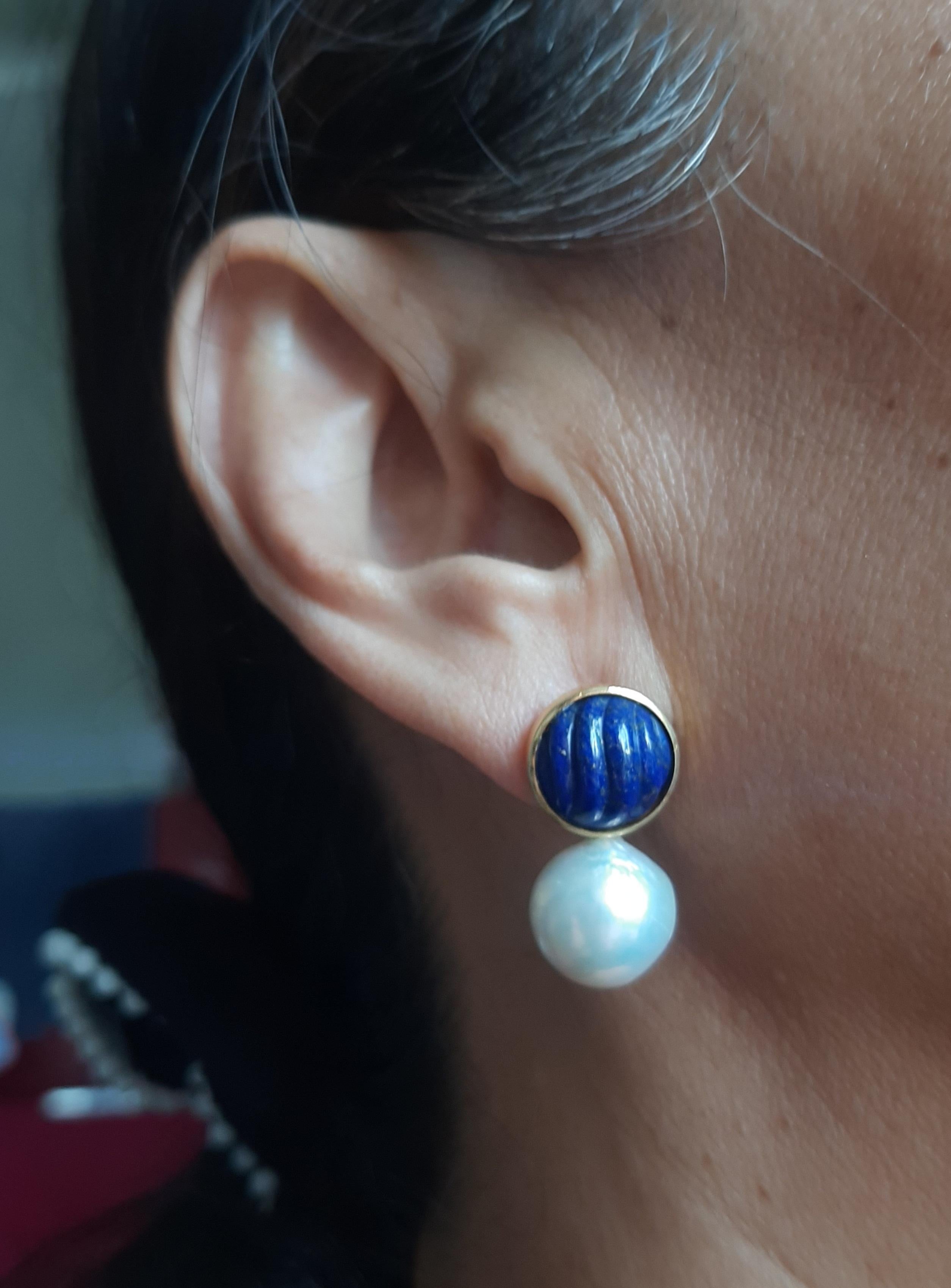 es boucles d'oreilles simples mais élégantes, faites à la main, sont composées de deux cabochons ronds en lapis-lazuli de 13 mm de diamètre, sertis dans un chaton en or jaune 14 carats au sommet duquel sont suspendues deux perles baroques blanches