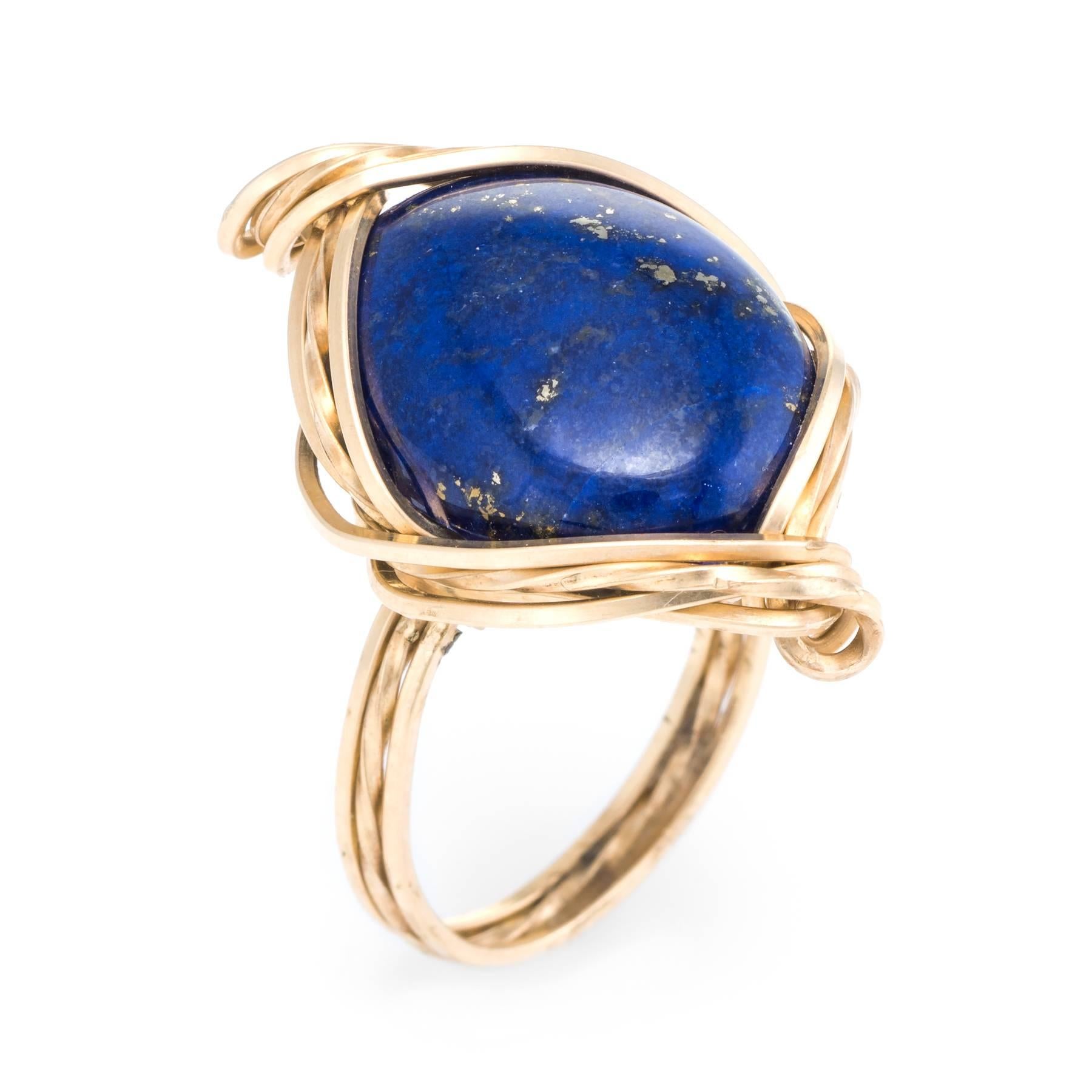 Elegant vintage cocktail ring (circa 1960s to 1970s), crafted in 14 karat yellow gold. 

Centrally mounted cabochon cut lapis lazuli measures 18mm x 16mm. The lapis is in excellent condition and free of cracks or chips.   

Unique coiled design