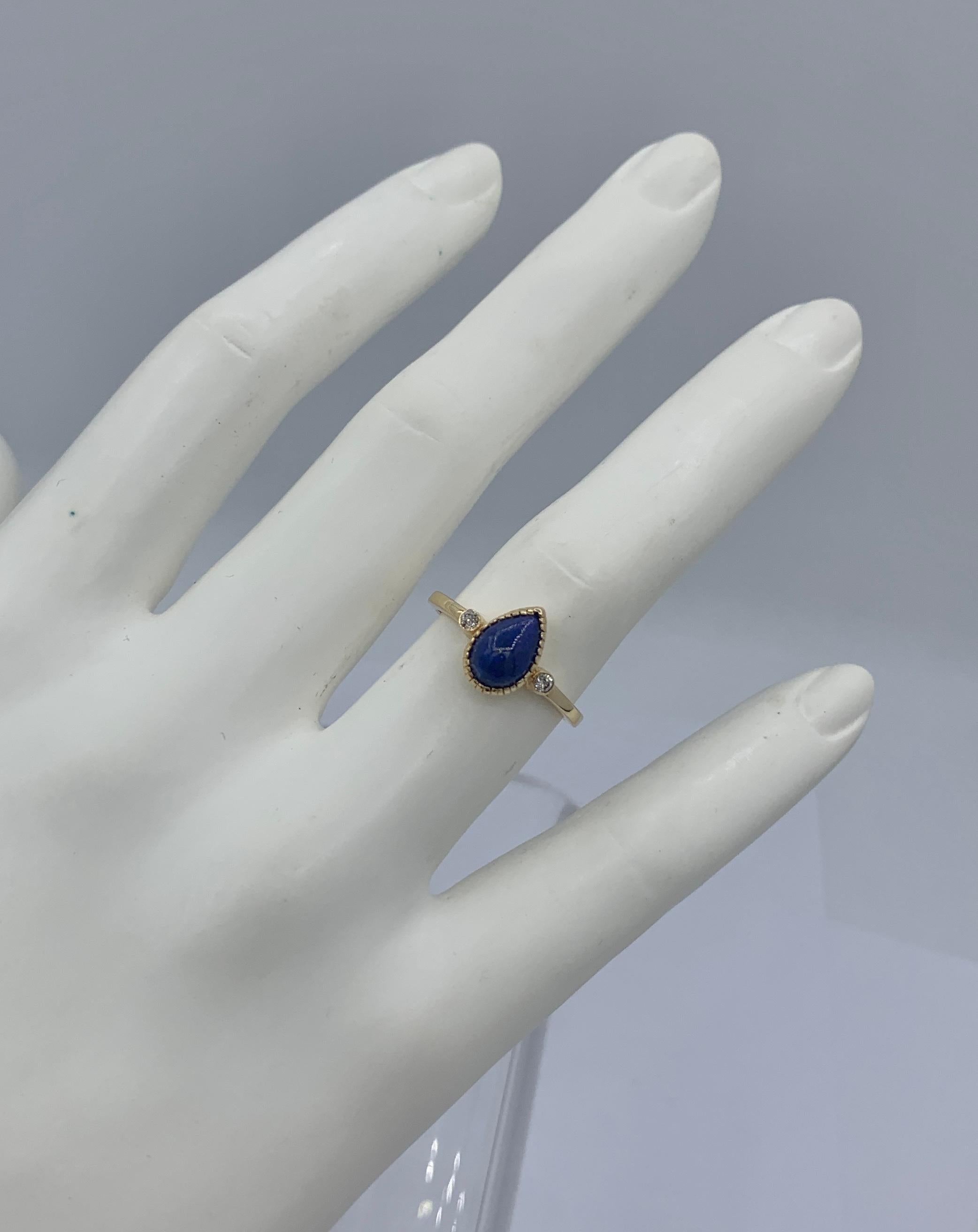 This is a gorgeous Mid-Century Modern Lapis Lazuli Diamond Ring in 14 Karat Yellow Gold.  The ring features a central blue Lapis Lazuli pear shape cabochon of great beauty.  The color of the lapis is gem quality blue.
On either side of the lapis are