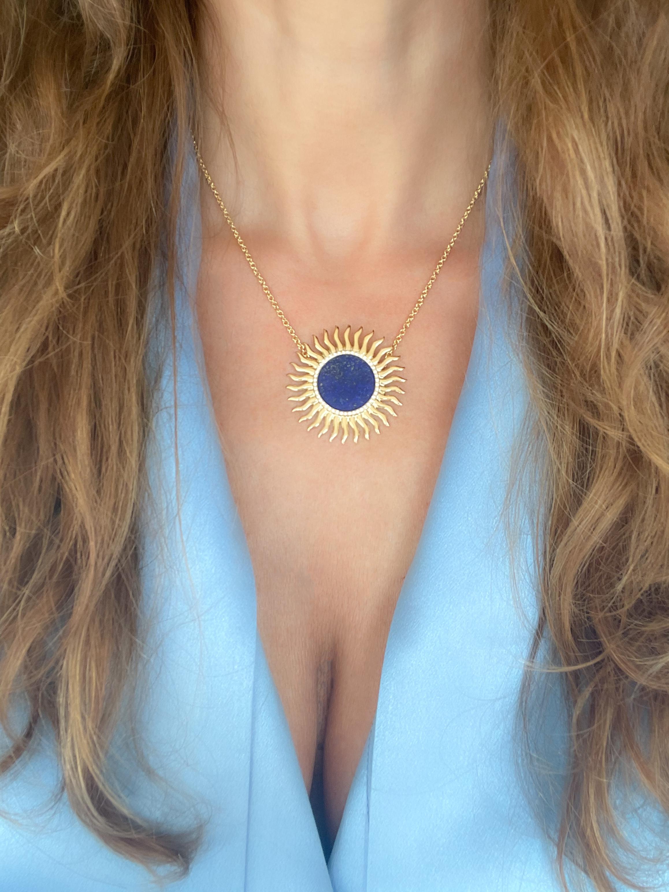 The solar-shaped pendant is crafted in 18k yellow gold and paired with lapis lazuli edged by 45 round brillant cut white diamonds for 0.18 ct. The solar gold ornament measures ≈ 1 1/2