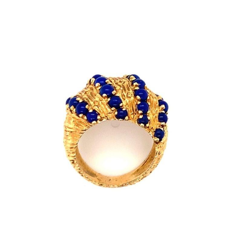 Une bague dôme en or jaune 18 carats en lapis-lazuli avec des perles de lapis mesurant chacune deux millimètres de diamètre. Le tout est rehaussé d'une monture à la finition dorée très texturée, avec des poinçons italiens.

Audacieux, royal,