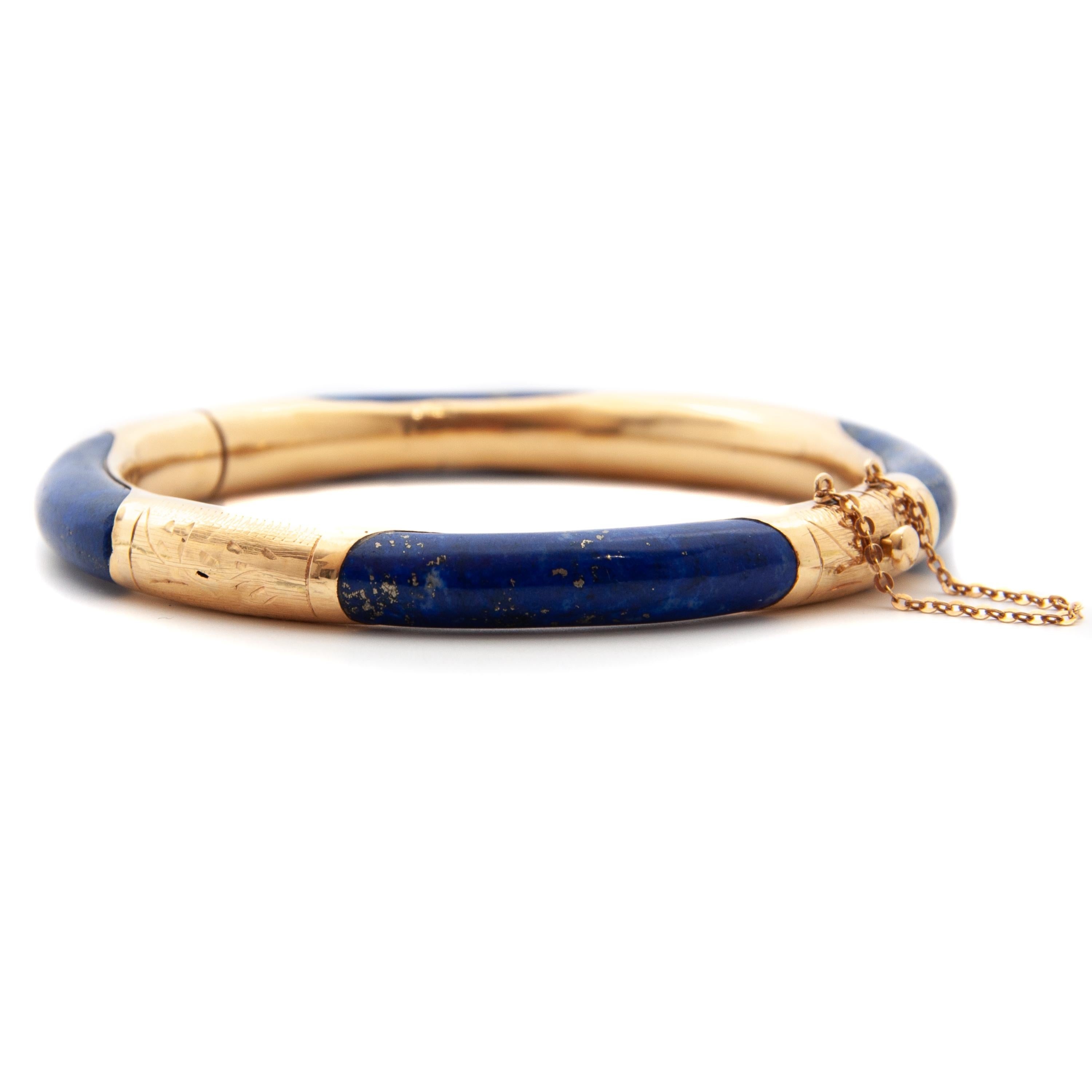 Gorgeous vintage lapis lazuli bracelet from mid-20th century. This lovely piece features a smooth blue stone from lapis lazuli, which is set within a 14 karat gold setting. The bracelet is hinged and has beautifully etched motifs. The lapis is