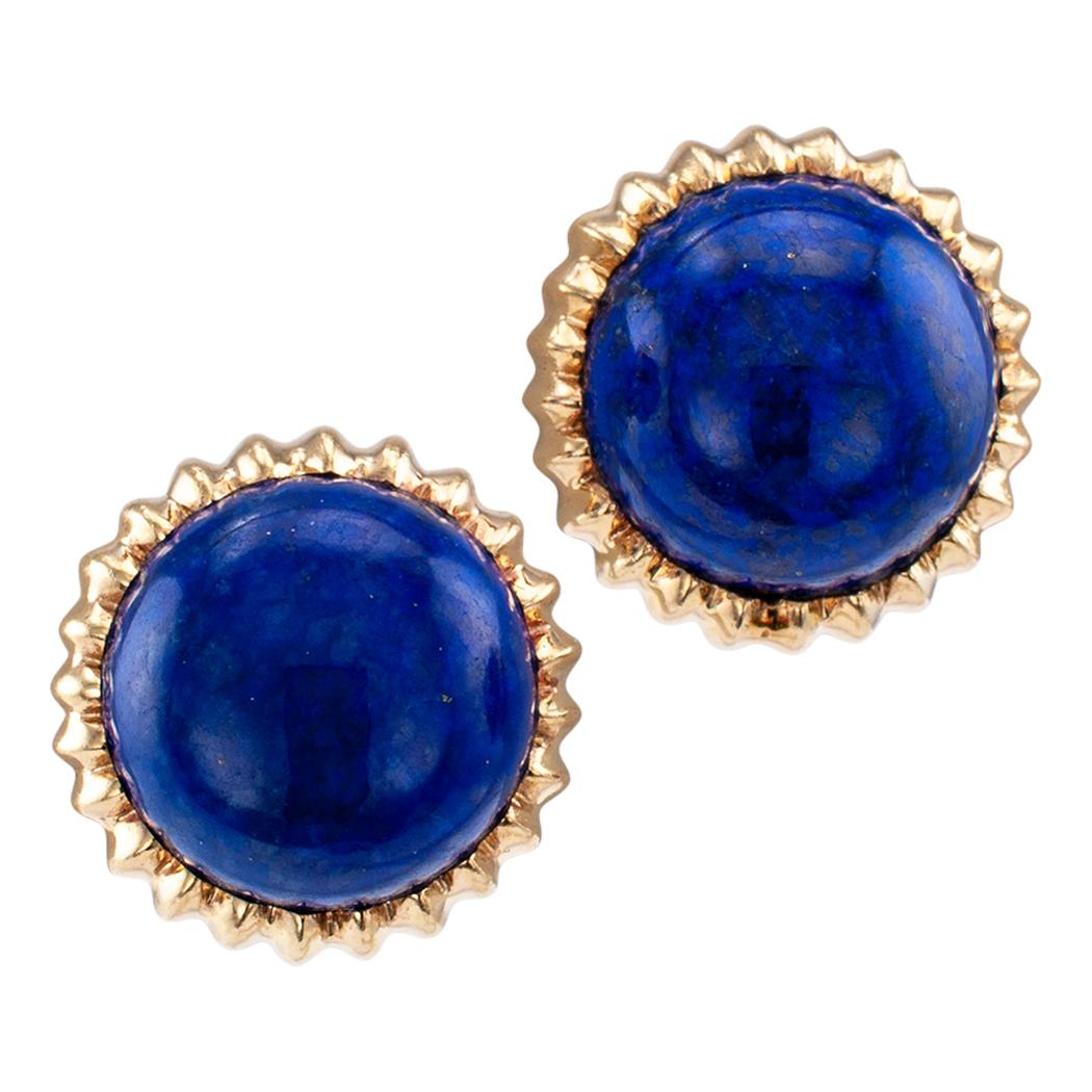 Lapis lazuli  gold ear clips circa 1970. Featuring a pair of high domed round lapis lazuli cabochons set in fluted bezels with omega clip backs, mounted in 14-karat yellow gold. We love the intense blue color of these well-matched lapis lazuli