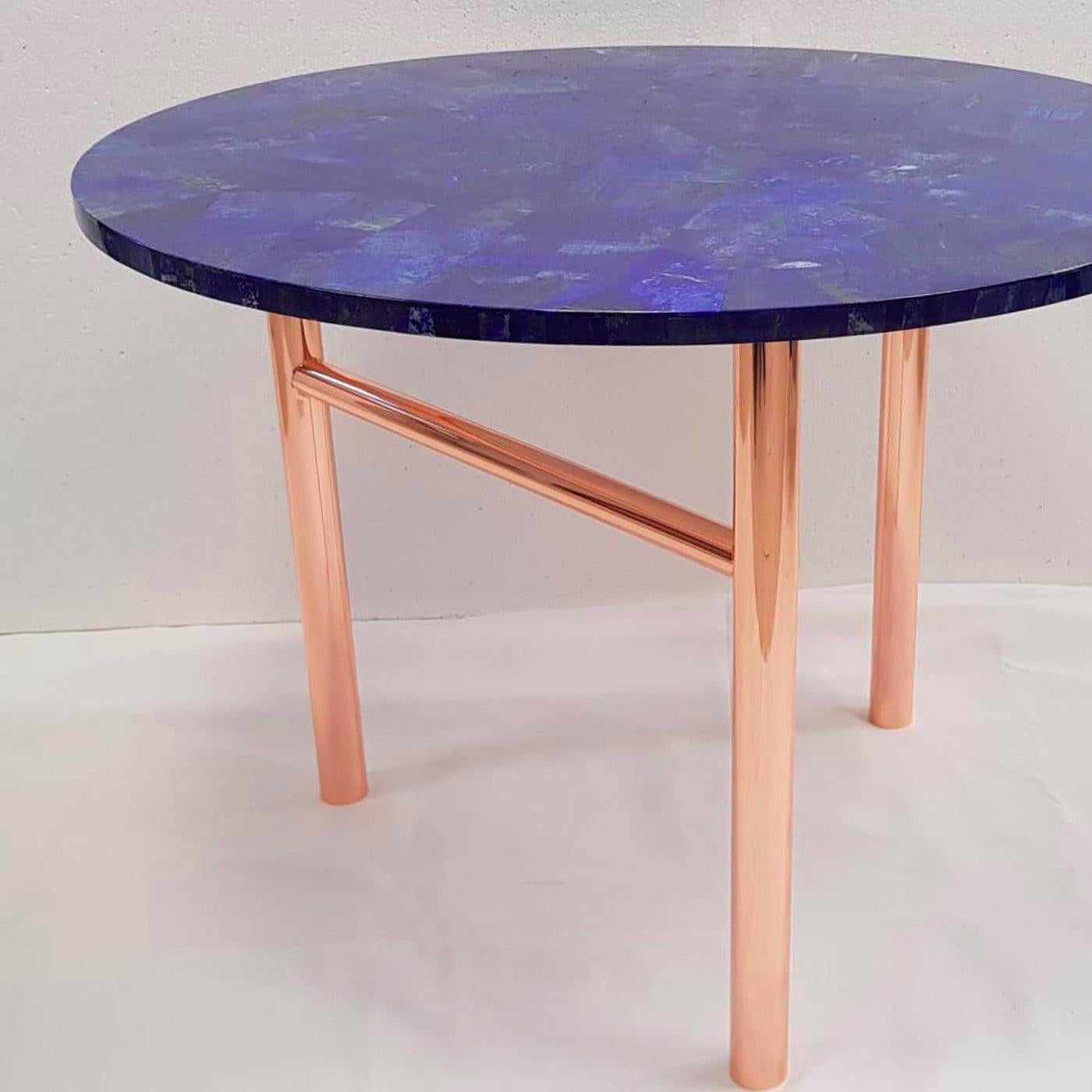 Manufactured through a mosaic technique that combines thin layers of precious lapis lazuli's hard stone to create this opaque and intense-blue round top, this table features a luxurious and refined personality. The luminous tubular base in brass