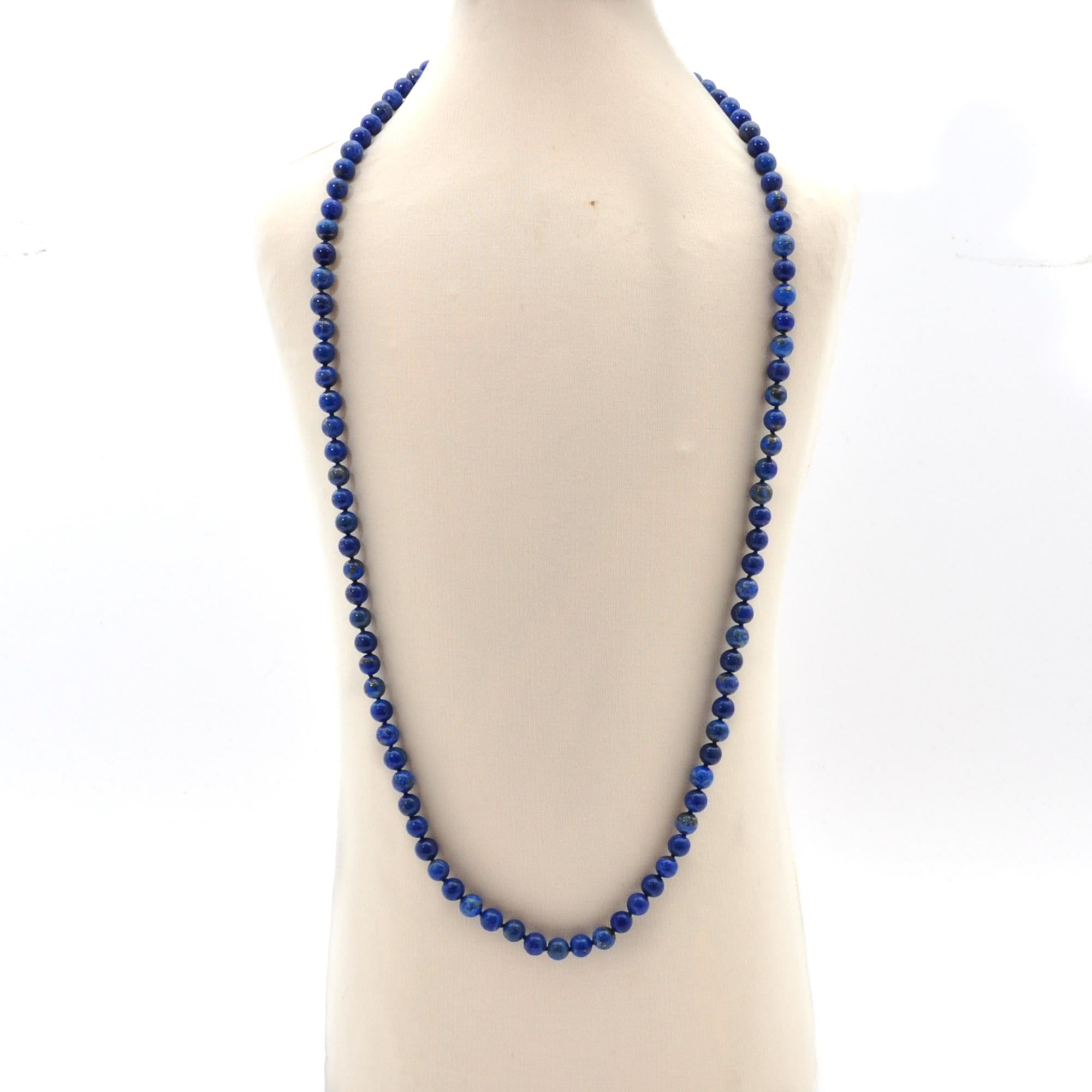 A Mid 20th Century lapis lazuli single strand necklace set with a gold ball clasp. The lapis lazuli is smoothly round polished and has a beautiful blue hue and in this royal blue color displaying shimmery spots of gold throughout. Between the beads