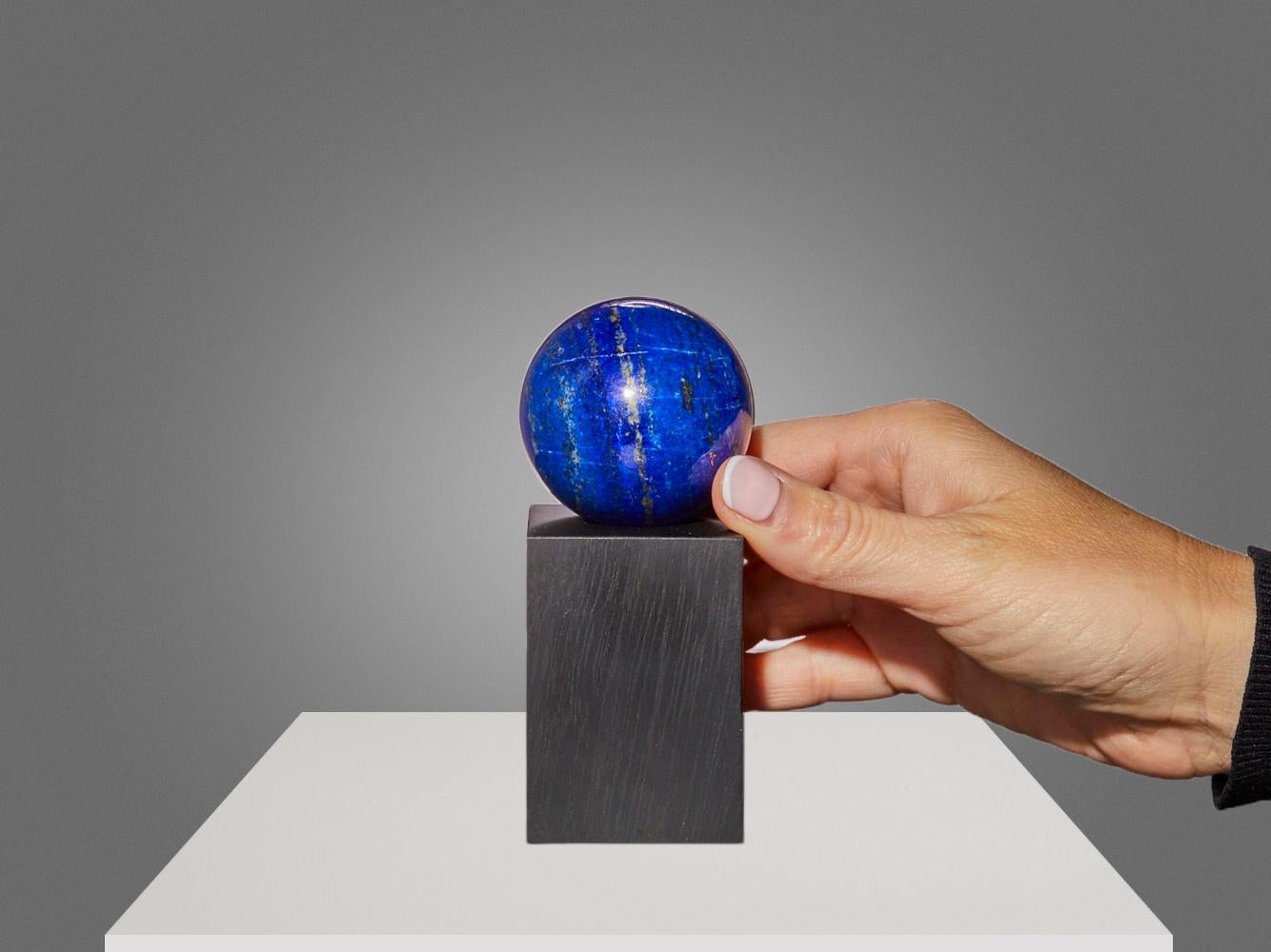 This captivating lapis lazuli sphere from Afghanistan features a deep, royal blue body accented with delicate veins of golden pyrite and soft white calcite.

Place of origin: Afghanistan
Height (Including Stand): 11 cm
Dimensions: Diameter 5