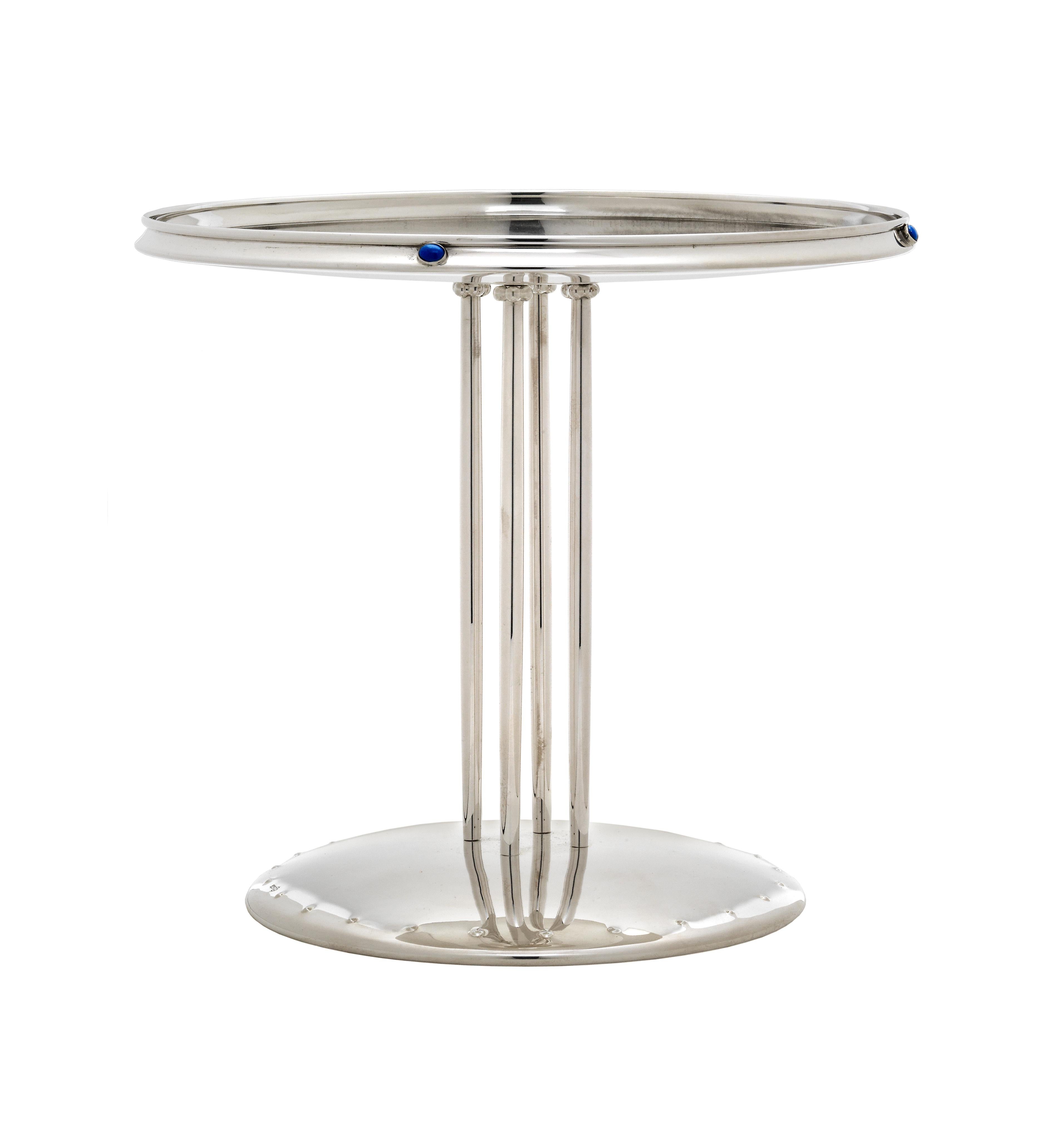 This sculptural centerpiece is made from an early design by Josef Hoffman. Its pure, long-legged physique and the smooth surface of its base are revolutionary. Its only adornment consists of four semi precious stones. Designed in 1902, this