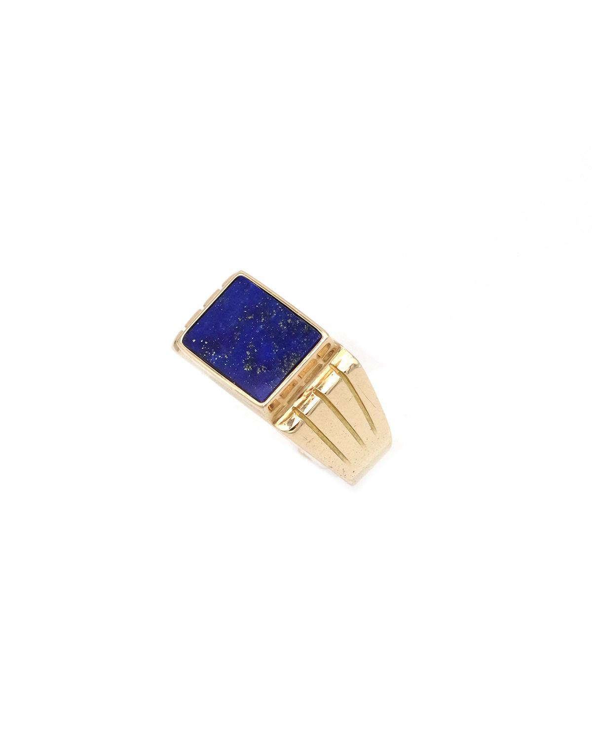 Lapis lazuli tank ring in 18 karat gold. Solid gold signet ring centered with a rectangular lapis lazuli plaque in a bezel setting. The shoulders of the ring are adorned with three parallel raised lines. The lapis has a beautiful, intense blue