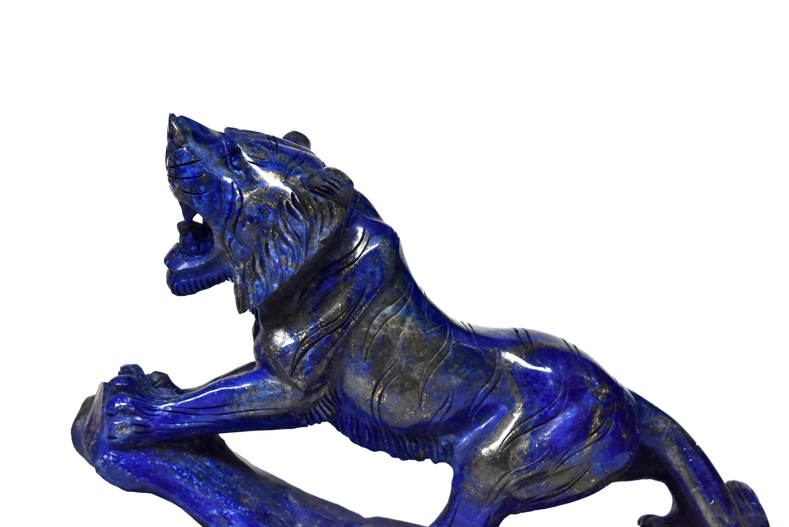 A beautiful all natural lapis lazuli tiger sculpture. The 2.5 lb violet blue stone has stunning glittering of gold, a contrast that creates a mesmerizing visual effect. Fantastic carving work renders realistic muscles and paws. This particular stone