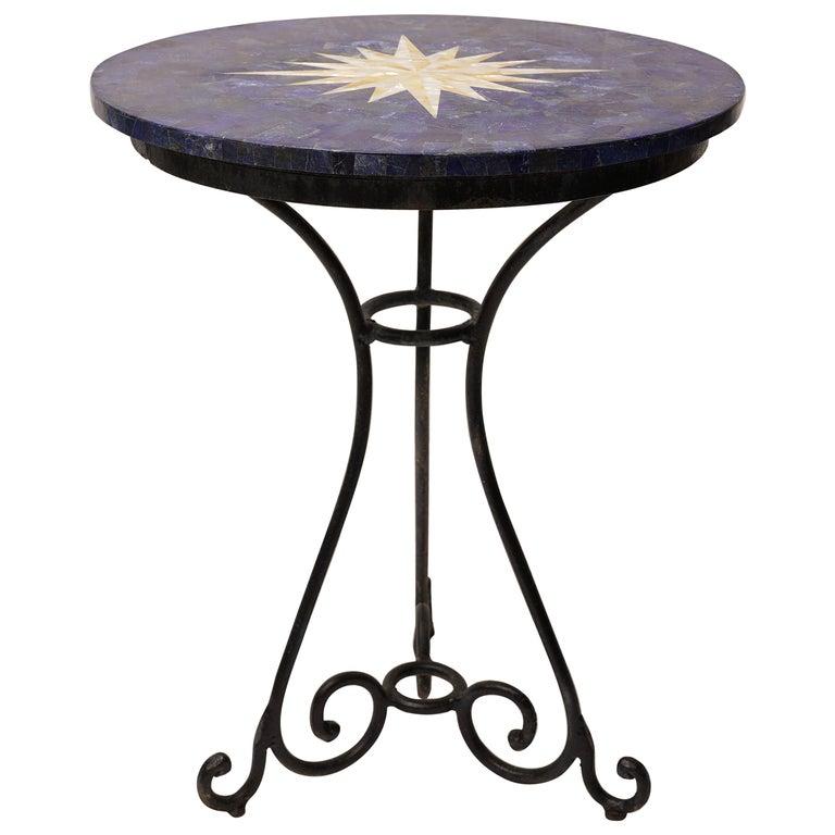 An unusual café table for your porch, patio or kitchen. The base and chairs are a heavy and sturdy wrought iron. The pietra dura top is lapis lazuli with a mother of pearl and white marble inlay. It features a lovely compass rose design on the top.